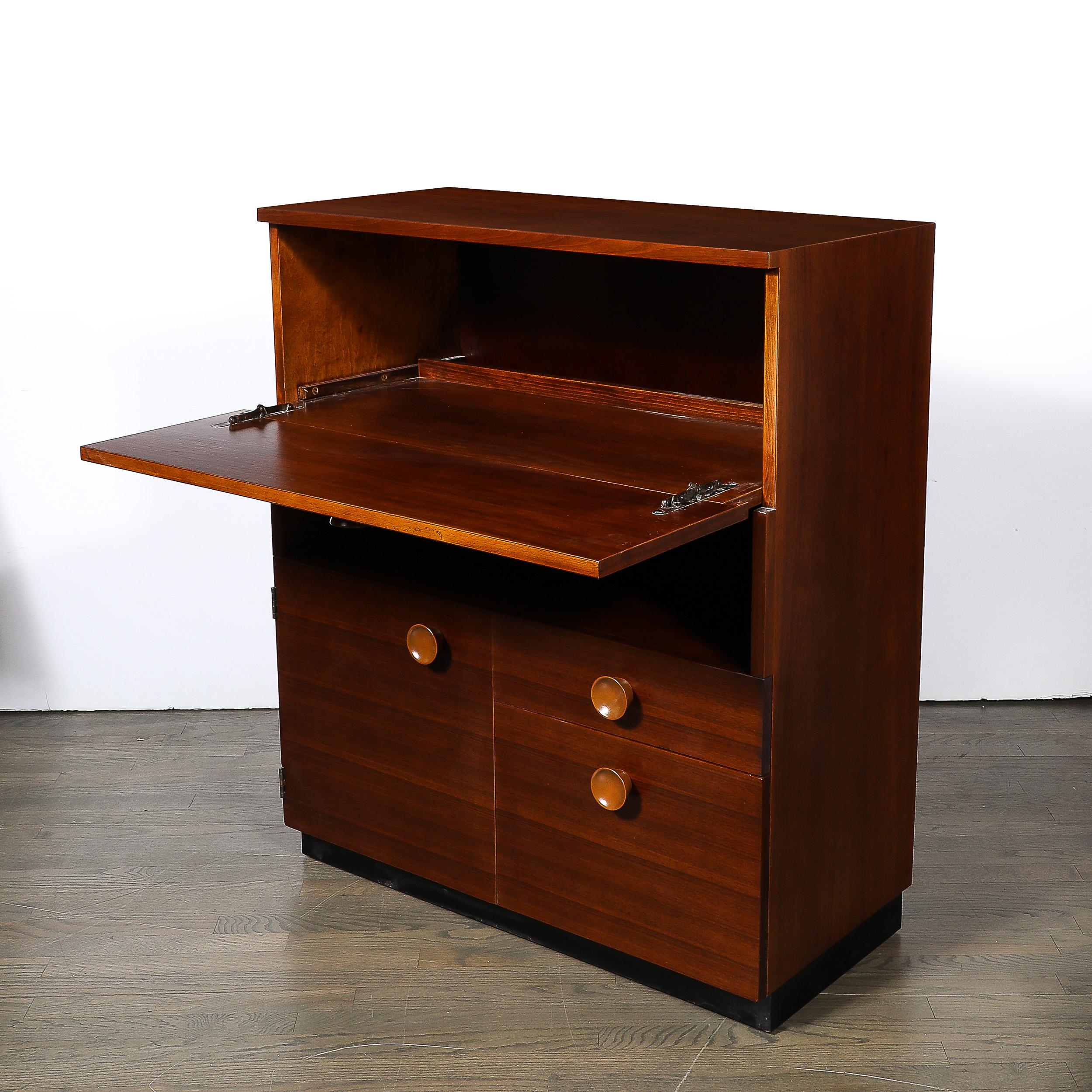 This rare and captivating Art Deco Drop Front Secreter Desk in Book-matched Hand-Rubbed Walnut is by the esteemed furniture designer Gilbert Rohde and originates from the United States, Circa 1942. Features a geometric construction in book-matched