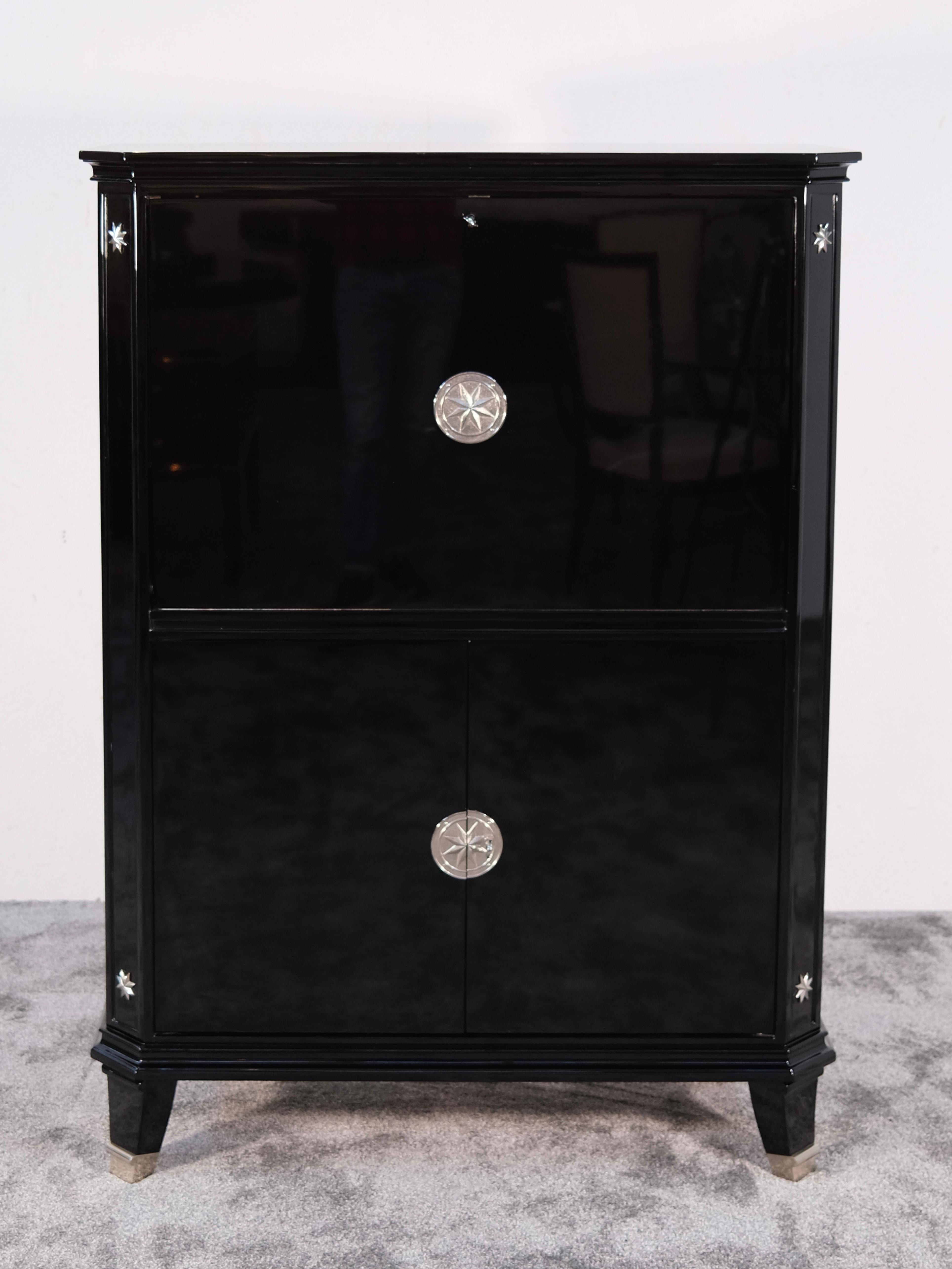 This striking Art Deco secretary cabinet — crafted in France during the 1930s — is a quintessential example of the era’s refined glamour and design ingenuity. Finished in a luxurious high-gloss black lacquer reminiscent of grand pianos, the piece