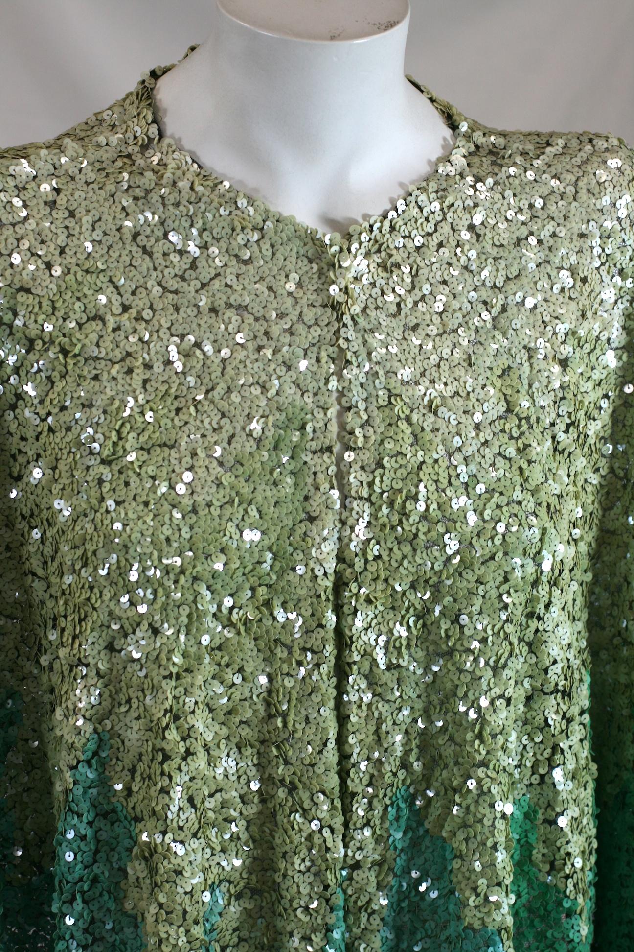 Art Deco French short evening cape, of a circular cut dipping slightly in front. Constructed from pale silk tulle embroidered with pale seafoam and turquoise-green round iridescent paillettes in a striking pattern.
Excellent condition.  1930's