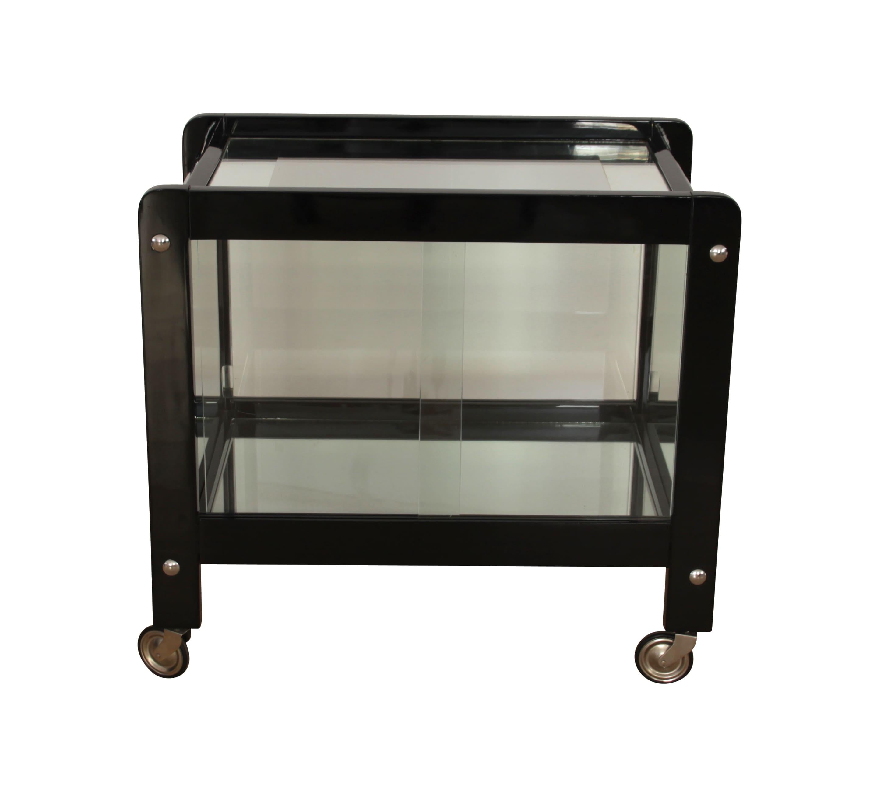 Elegant Art Deco serving table in black lacquered wood, chromed metal, glass and mirror, from France, circa 1930.
Black high-gloss lacquer on wood. Chromed metal hardware. Original old glass plate with silver-colored framing on the top plate.
Two
