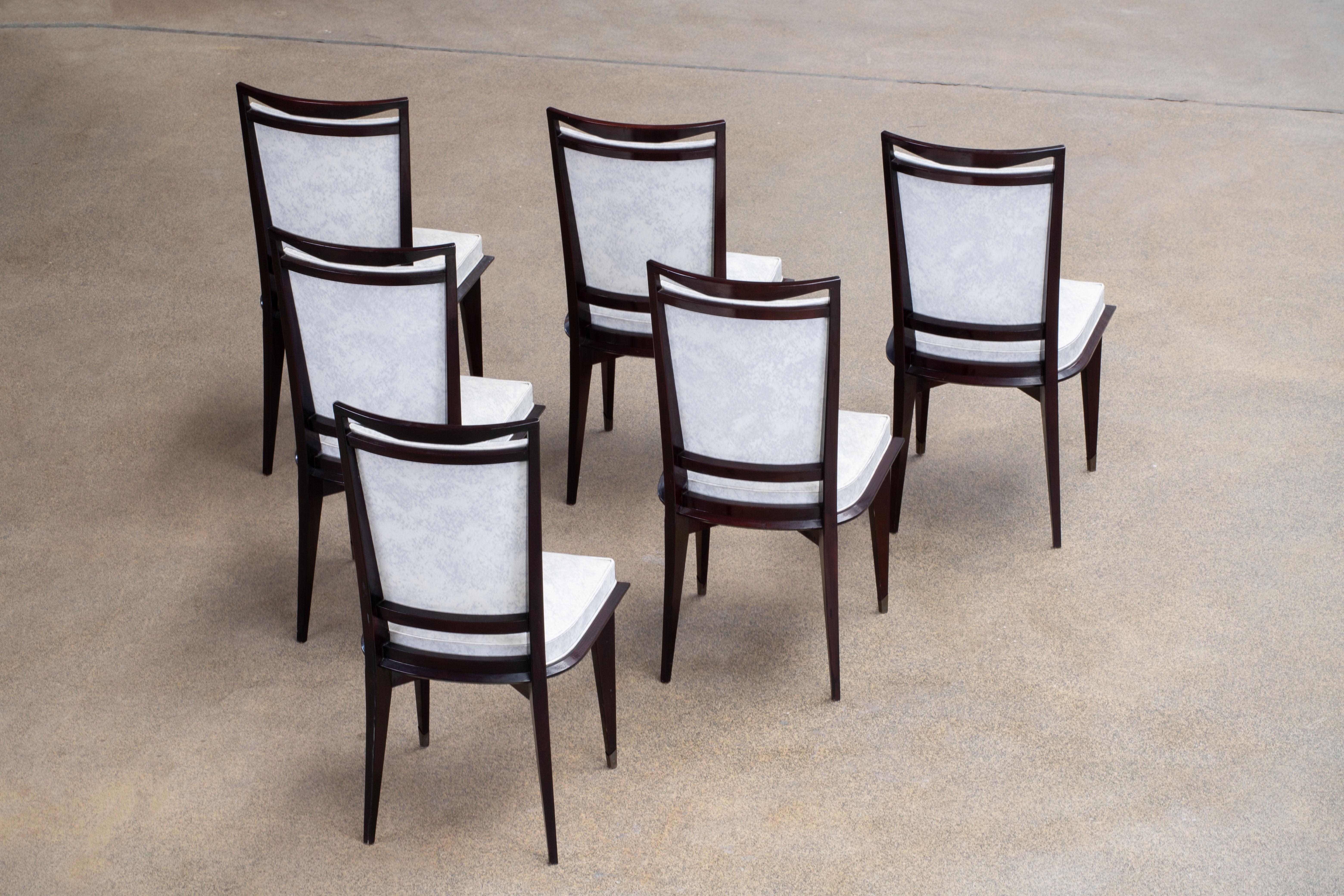 Set of six upholstered high back chairs covered in white vinyl, exhibiting traditional French design elements in a deep oak finish. Restored and polished.