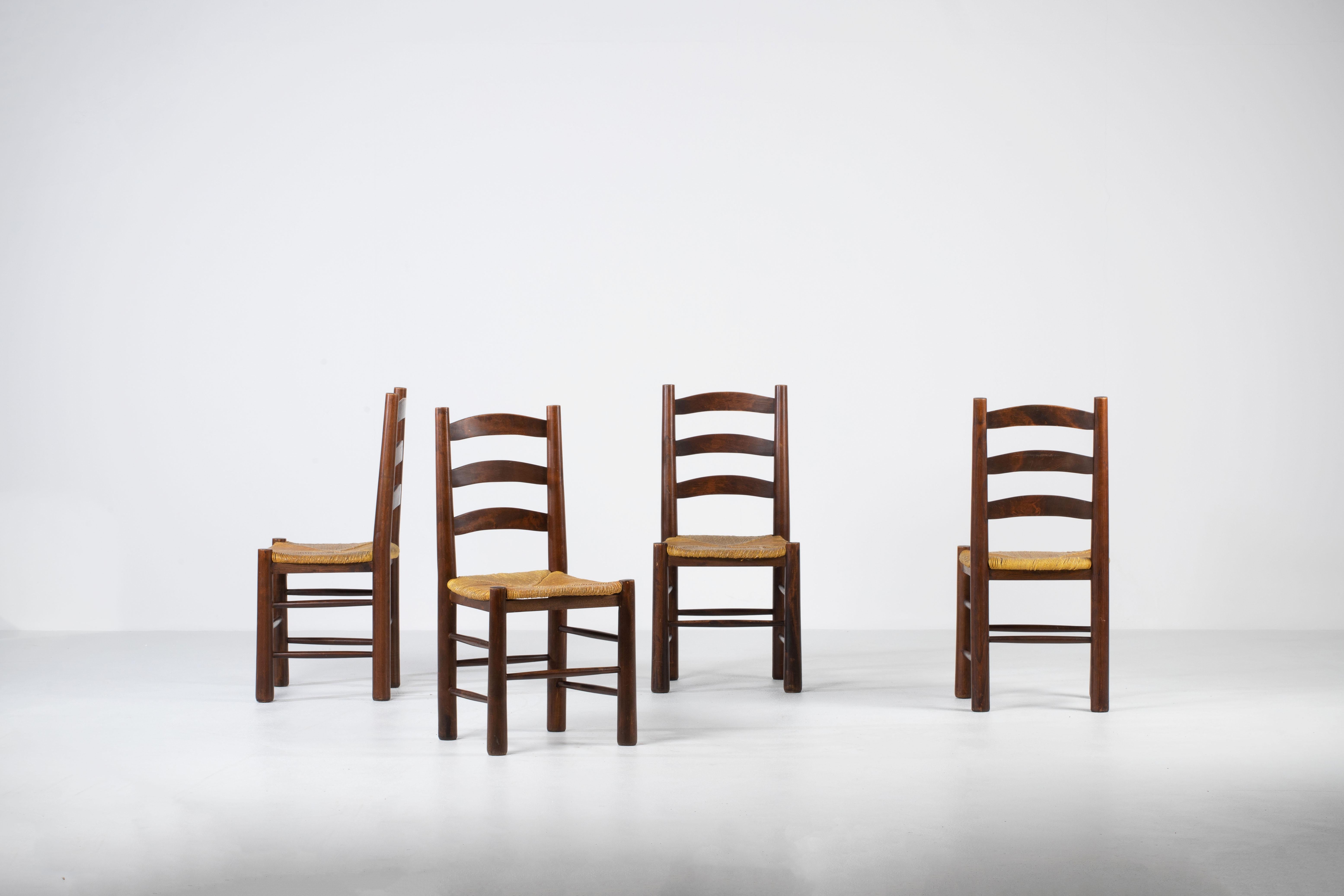 Un set di sei sedie da pranzo francesi di ottima fattura, ispirate alla filosofia del design di Charlotte Perriand. Realizzate in rovere massiccio, queste sedie incarnano l'eleganza rustica e la semplicità funzionale tipiche dell'artigianato