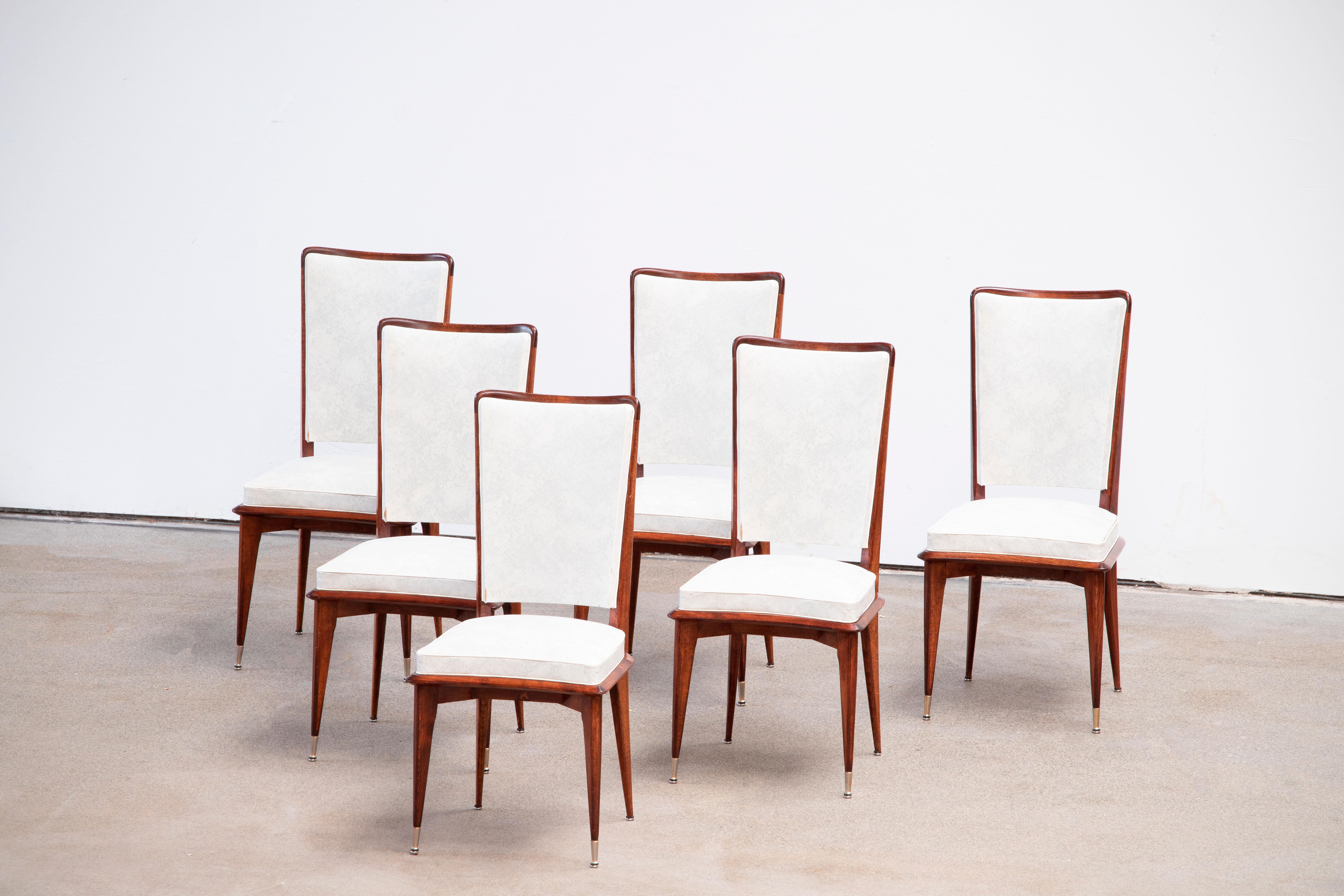 Set of six upholstered high back chairs covered in white vynil, exhibiting traditional French design elements in a deep oak finish. Restored and polished.