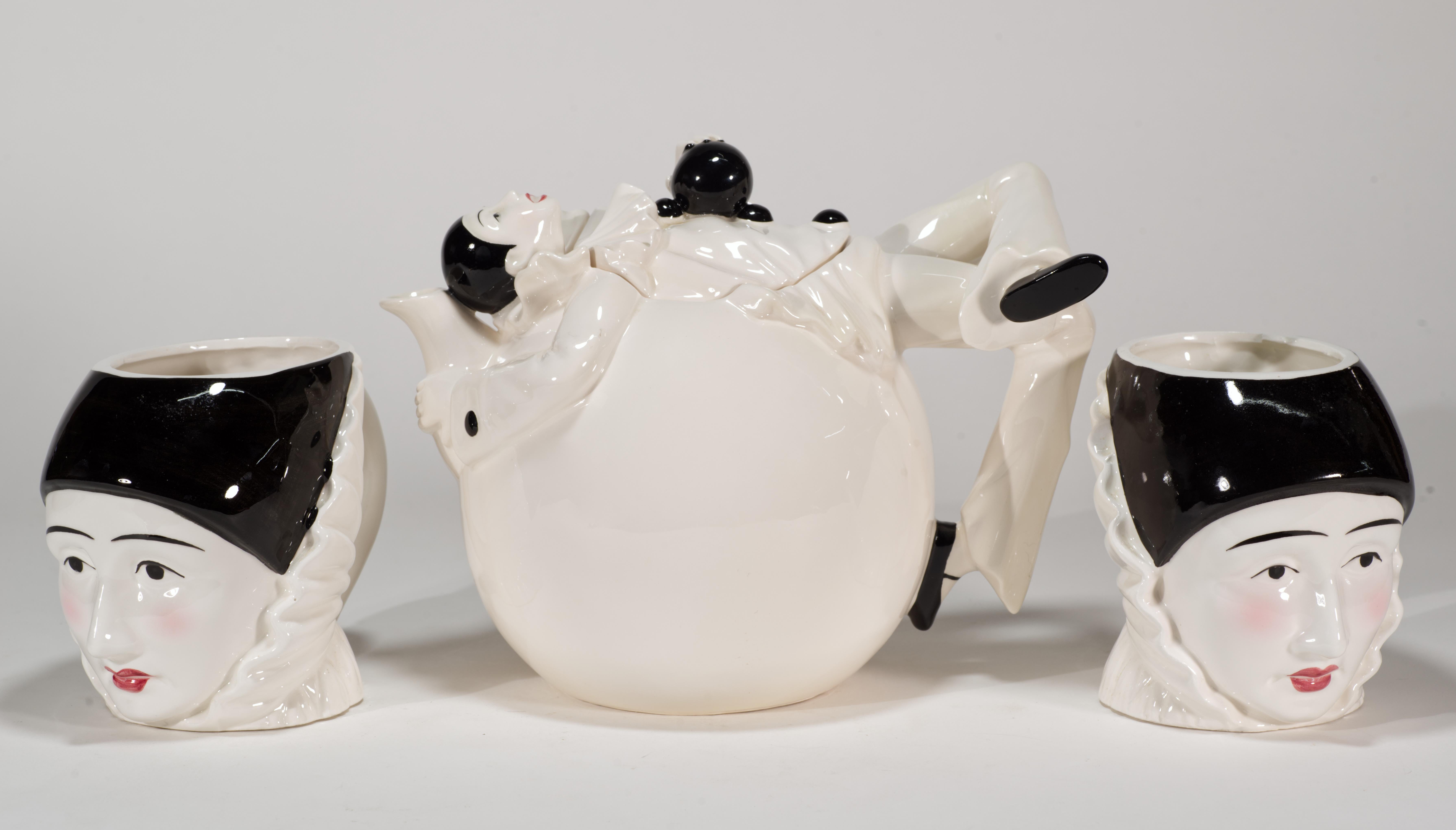 Vintage ceramic set of teapot and 2 mugs or cups features Pierrot or Harlequin sculpted decor in Art Deco style. Pierrot, one of the main male characters in French pantomime, is depicted with his usual sad face, black eyes and brows, red lips and