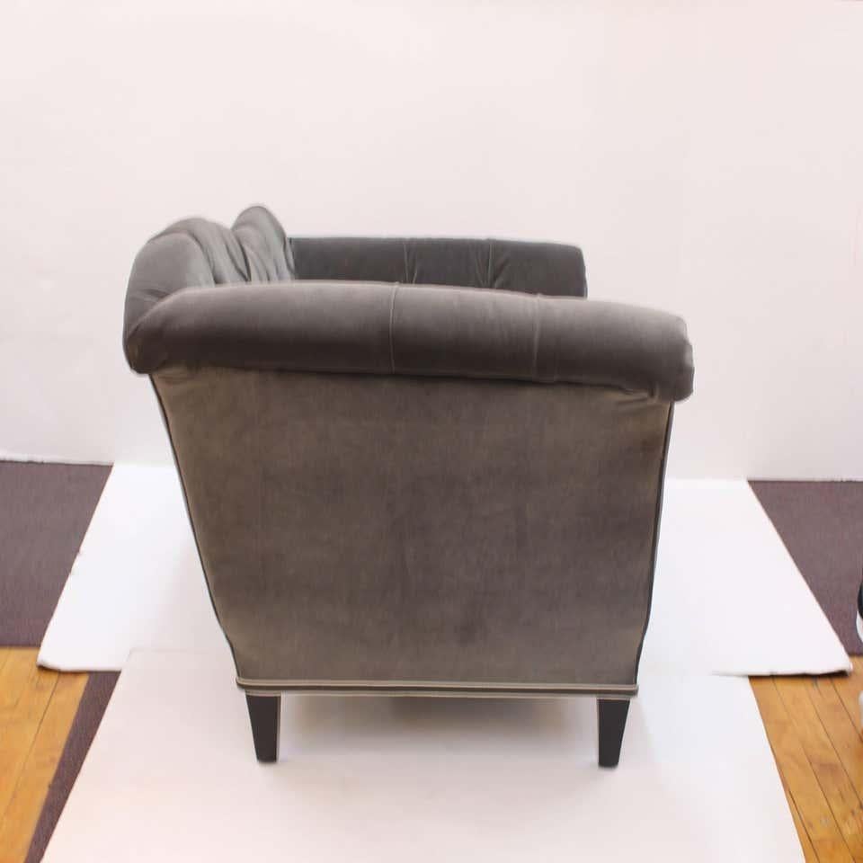 Art Deco settee with silver gray velvet tufted upholstery and curved back, standing on wooden legs with black finish. One settee with a high right back and one settee with a high left back is available. Details include double cording around the