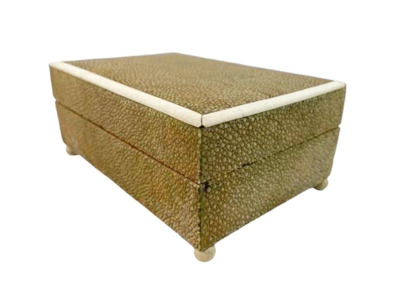 Caja Art Decó revestida de piel de raya verde oliva con tapa de bordes de hueso elevada sobre pies de bola torneados y con el fondo cubierto de piel de serpiente o lagarto.
