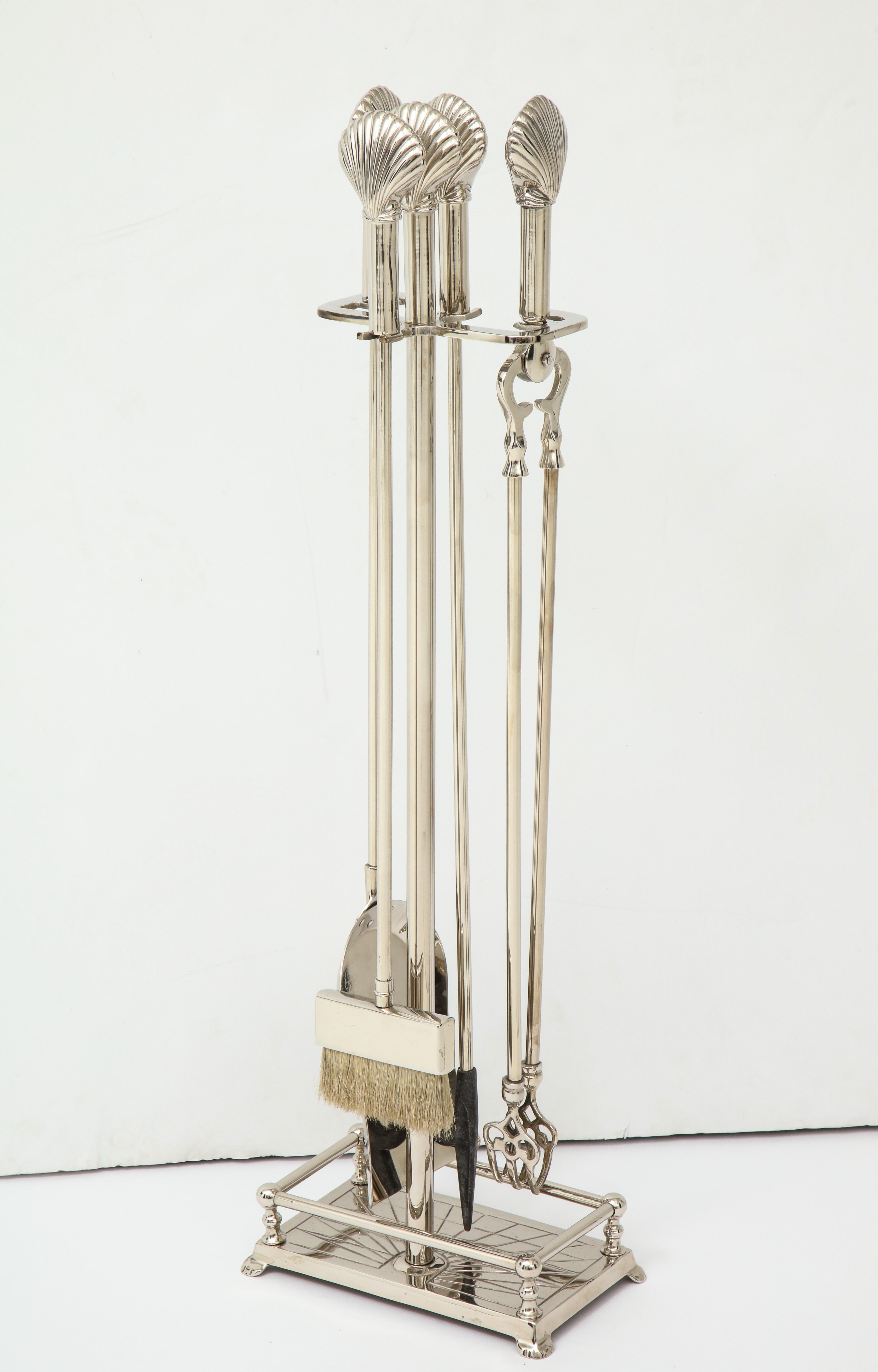 Set of Art Deco fireplace tools with stylized shell finials on tools and stand. Set includes poker, shovel, tongs, broom and Stand, all in polished nickel.