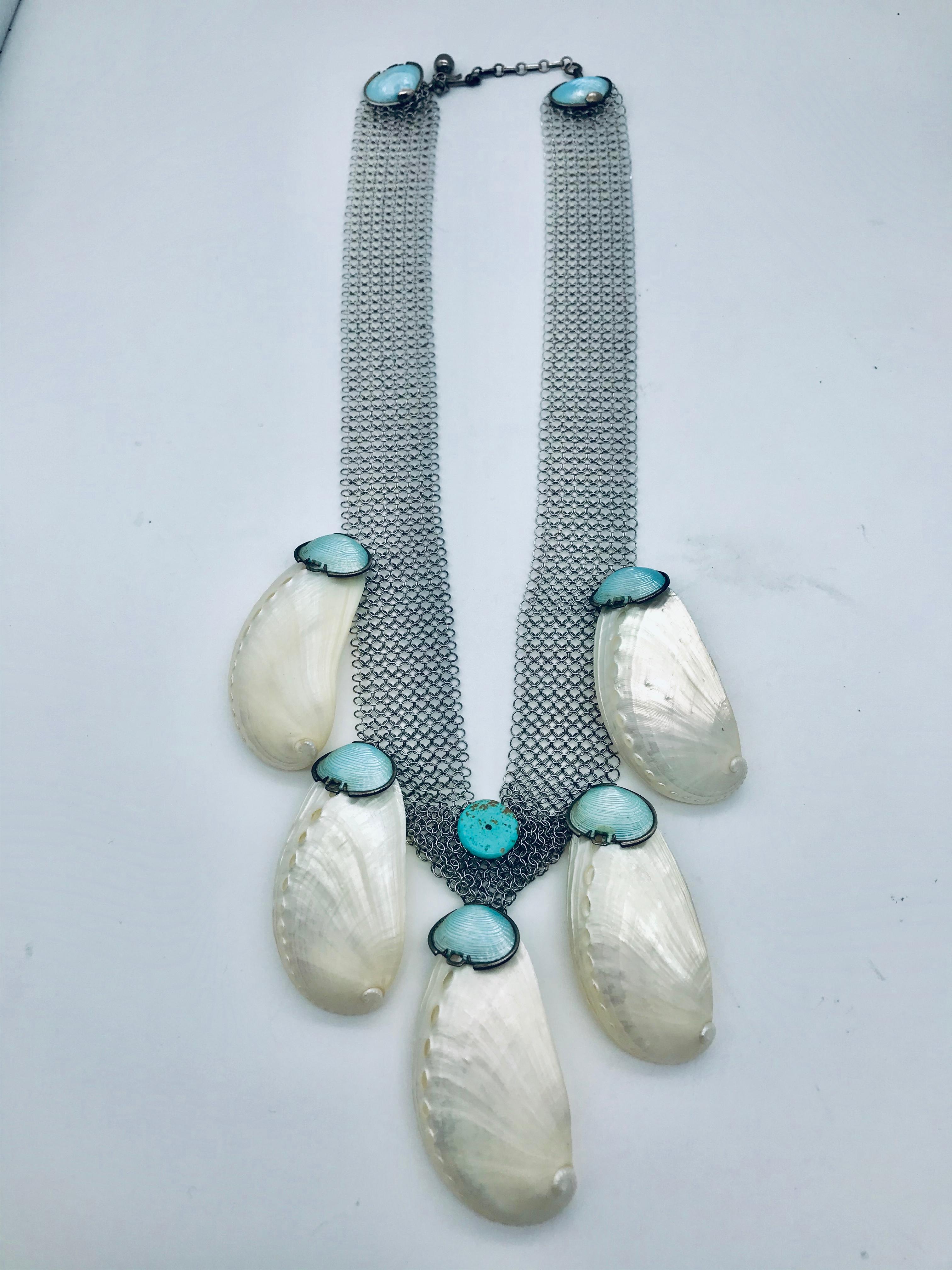 The Art -Deco Shell  necklace up-cycled with Stainless steel Mesh. Each white  shell is reinforced by use of architectural adhesive fusing  two shells together to create one object . Each natural shell is finished by Blue Enameled Deco Shell. These