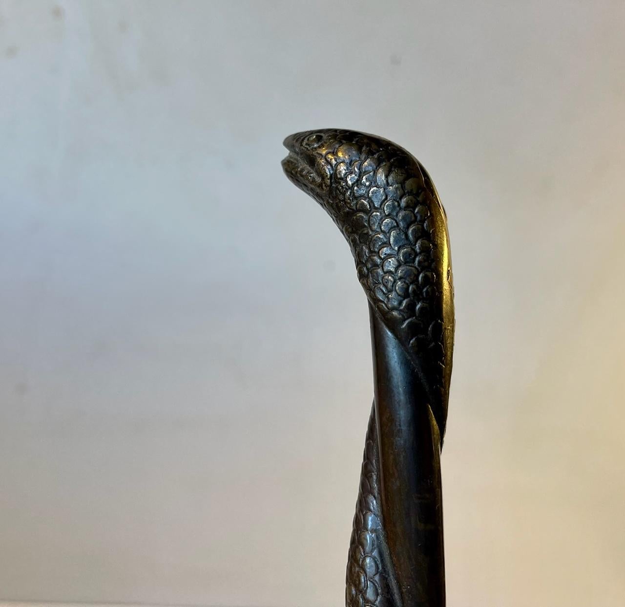 Elegant long shoe horn set with a stylised snake in bronze twisting around the center pole. It can be wall hung in your entrance. It was cast in Denmark circa 1930-40, probably by N. Jal or N.D.R. Measurements: L: 44 cm. The 'horn' it self measures: