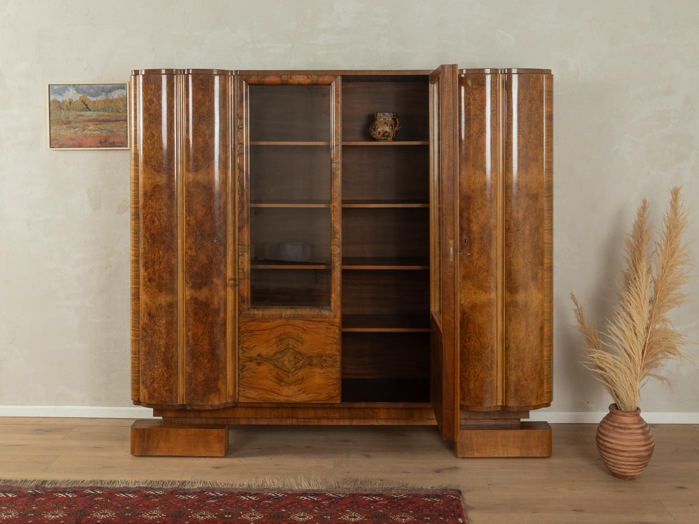 Unique Art Deco Showcase from the 1920s. High-quality corpus in walnut veneer with two glass doors, twelve shelves, two doors and contemporary feet.

Quality Features:
very good workmanship
high-quality materials
Made in Germany