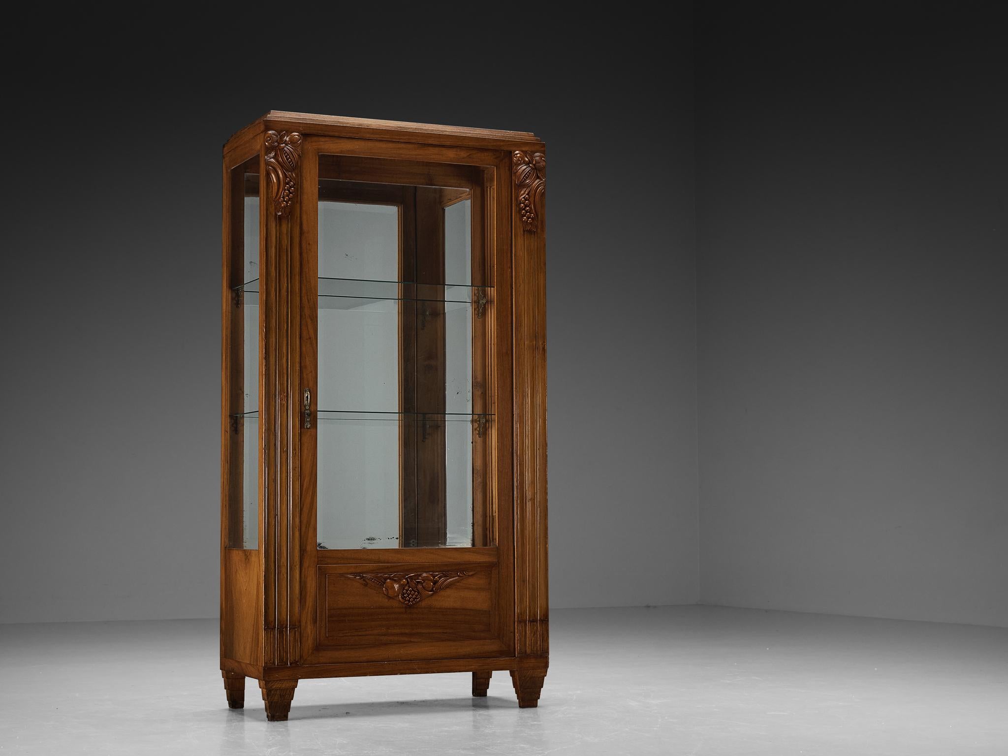 Vitrine, walnut, mirrored glass, glass, brass, Europe, 1940s.

This wonderful Art Deco showcase is made in Europe in the 1940s and is executed in partially carved walnut wood. This showcase displays exquisite detailing in the shape of decorative