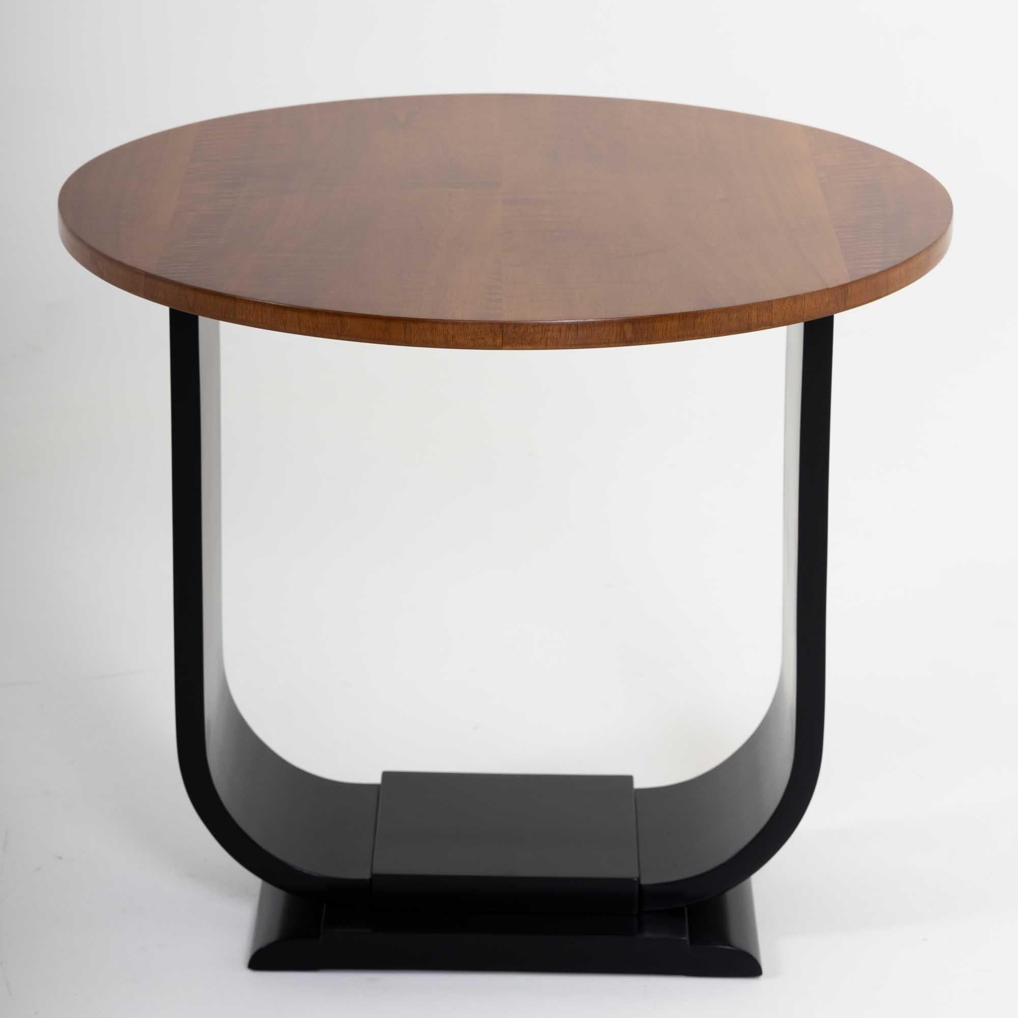 Small Art Deco side table with a round table top. The veneered table top forms an elegant contrast to the U-shaped ebonized base.