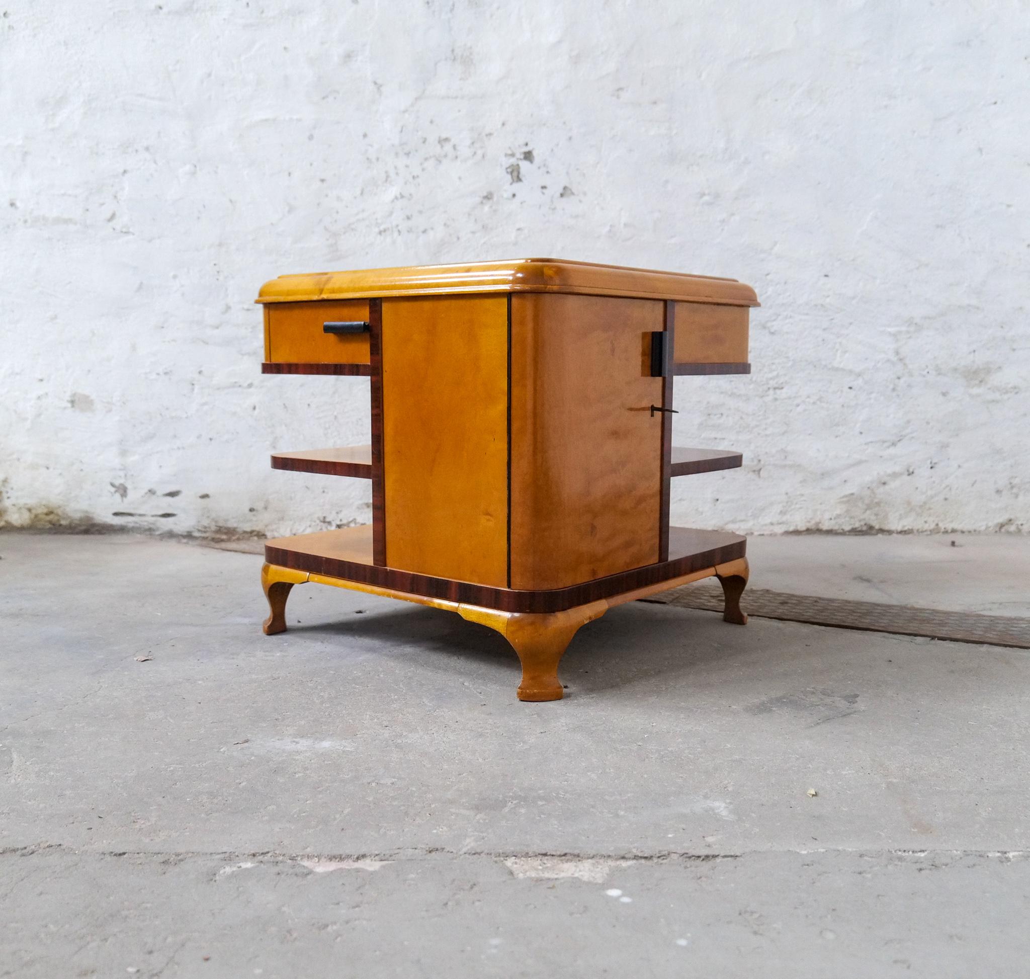 Sophisticated and crafted coffee/side or dry bar table made in the 1930s Sweden. 
The table is made with two doors and two drawers together with shelves. ITs made in veneer of mahogany and birch. On the top you find the typical inlays of wood
