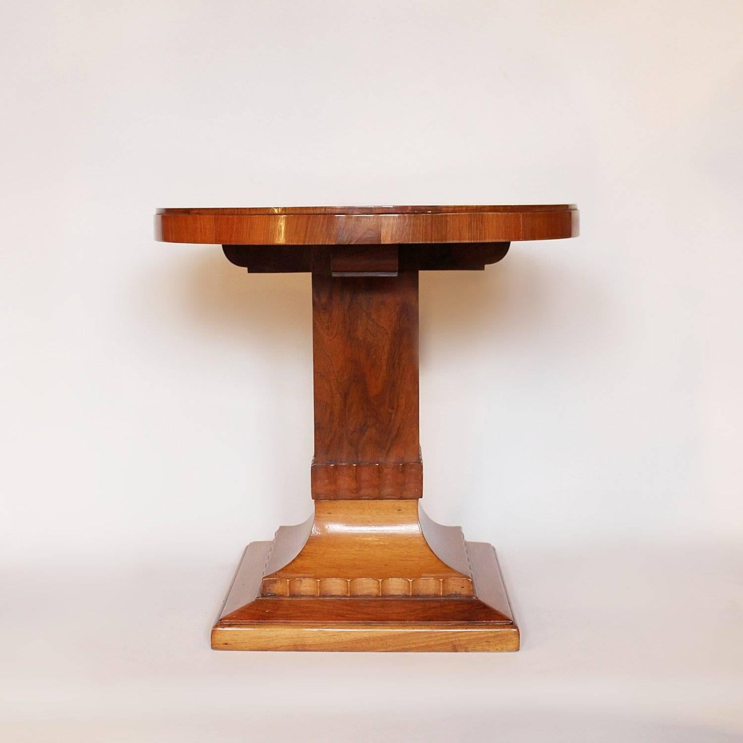 An Art Deco side table in figured walnut, set over a shaped pedestal and stepped, base with fluted detail.

 