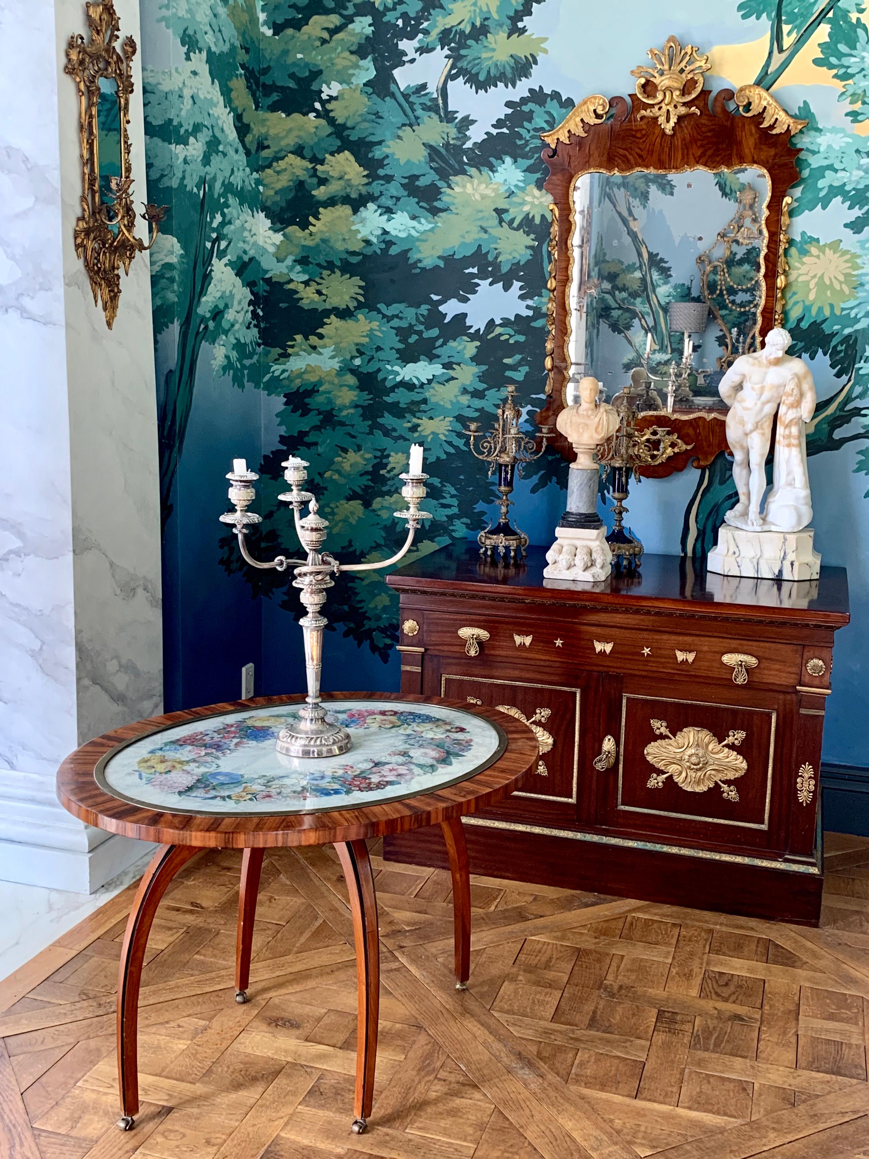 This beautiful kingwood side table has a hand-painted floral wreath and is protected under a glass and is framed in brass.