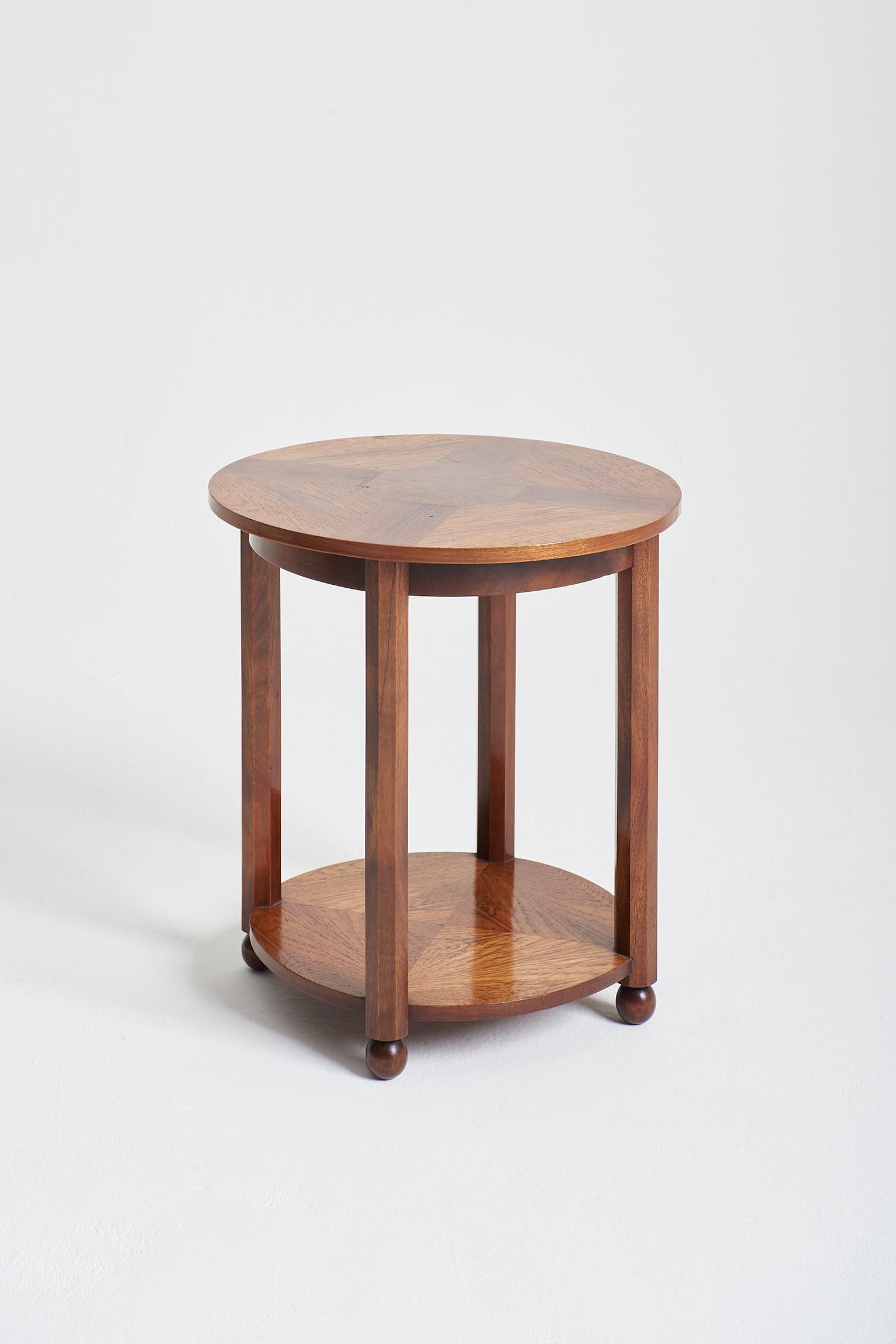 An Art Deco two-tiered oak, mahogany and burr walnut side table, the two circular tops adorned with geometric parquetry supported by four solid octagonal legs on ball feet.
France, Circa 1930.