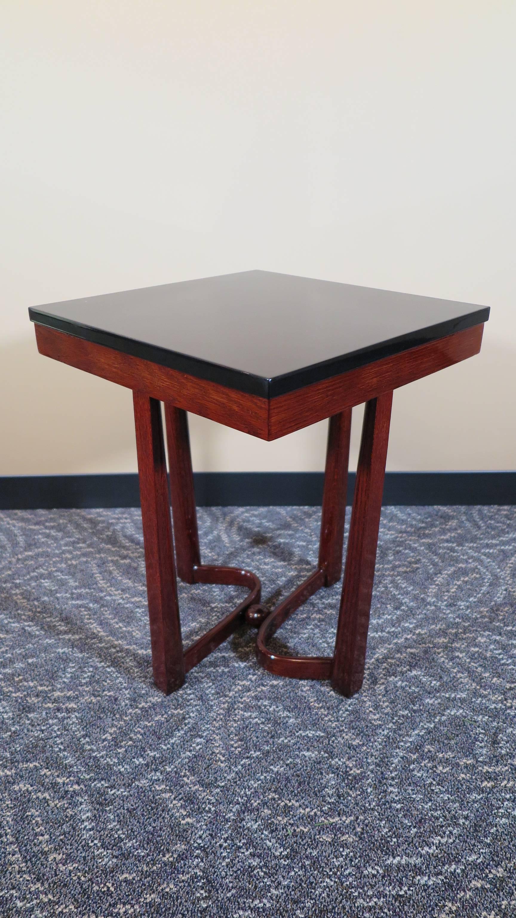 American Art Deco Inspired side table for Harry Baron Furniture.  Mahogany wood table, black lacquered top, reverse tapered legs, turned wood struts joined by a mahogany wood ball center.  In very good condition.   American 1945