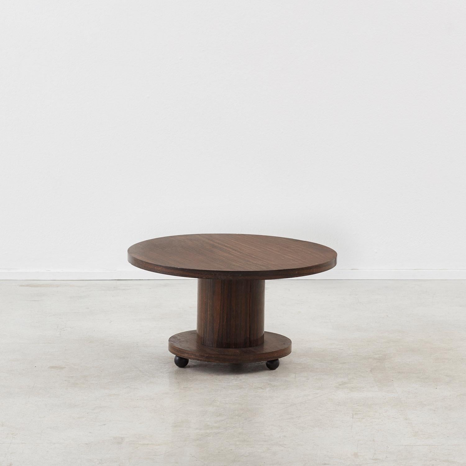 A well-proportioned Art Deco side table sat on fun spherical feet. The simplicity of the mirrored circular top and base is tempered by the richness of the rosewood veneer, which provides a pleasing visible grain.