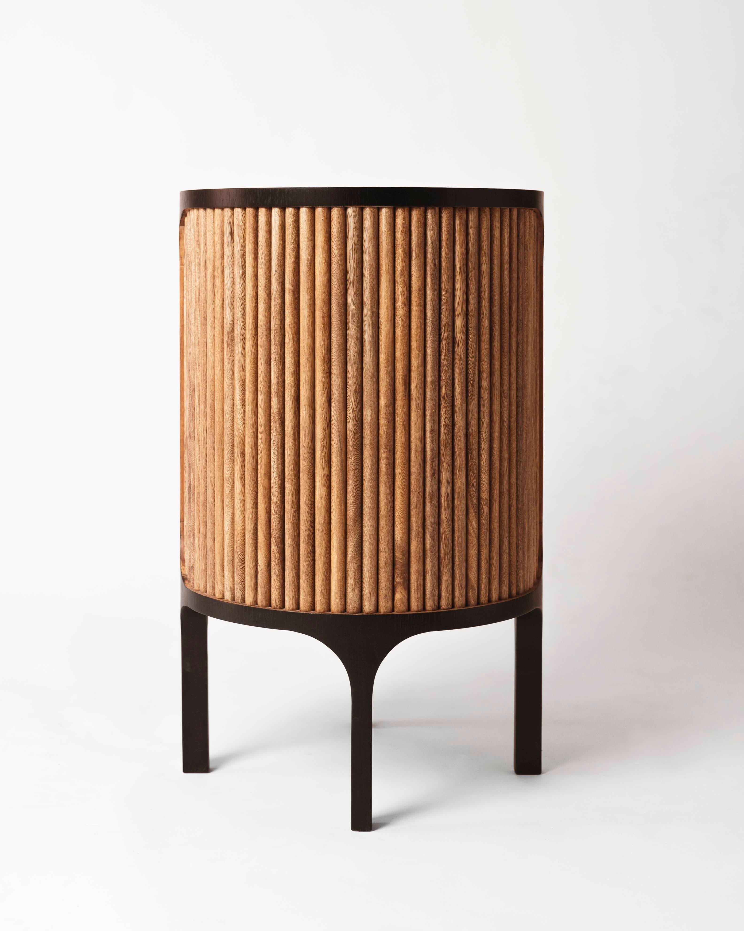 Wooden side table with a round top and two story shelves, made in oak veneer and tabebuia rosea.

This side table is inspired by the Art Deco movement in the 1920s that is marked by the use of geometric shapes, stylized curves, atmospheric lighting,