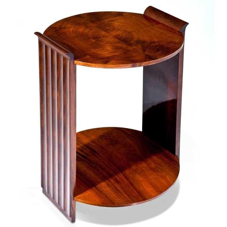 Art Deco side table of the 1920s in mahogany with two round tiers. The side panels show a fluted surface and round down at the top.