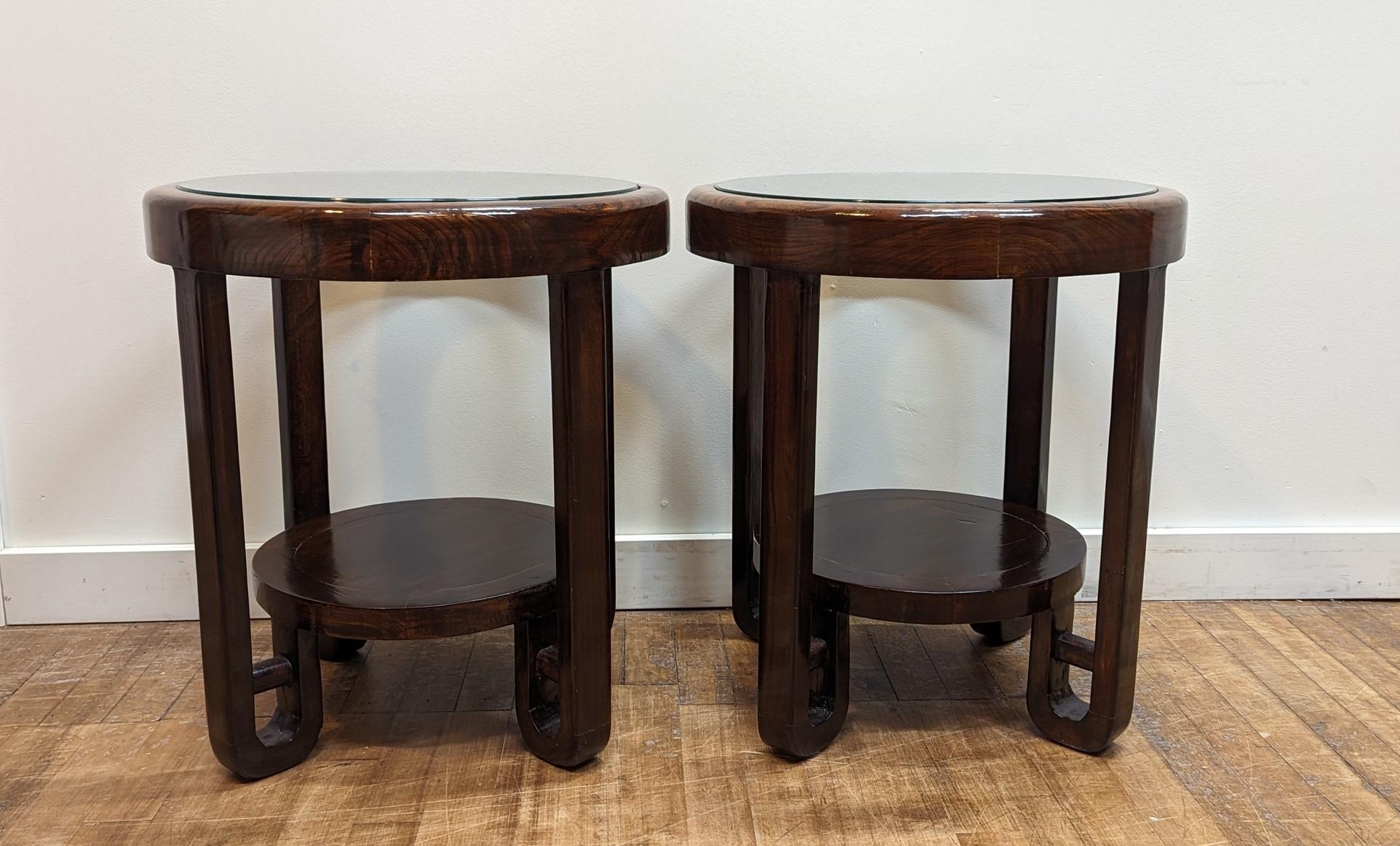 Pair of Art Deco style glass top side tables.  The tables are solid Elm Wood with thick glass inset tops.  Tables and tops are in very good condition.  One table has an indentation to the wood surface in the lower shelf.   Stunning pair of tables.  