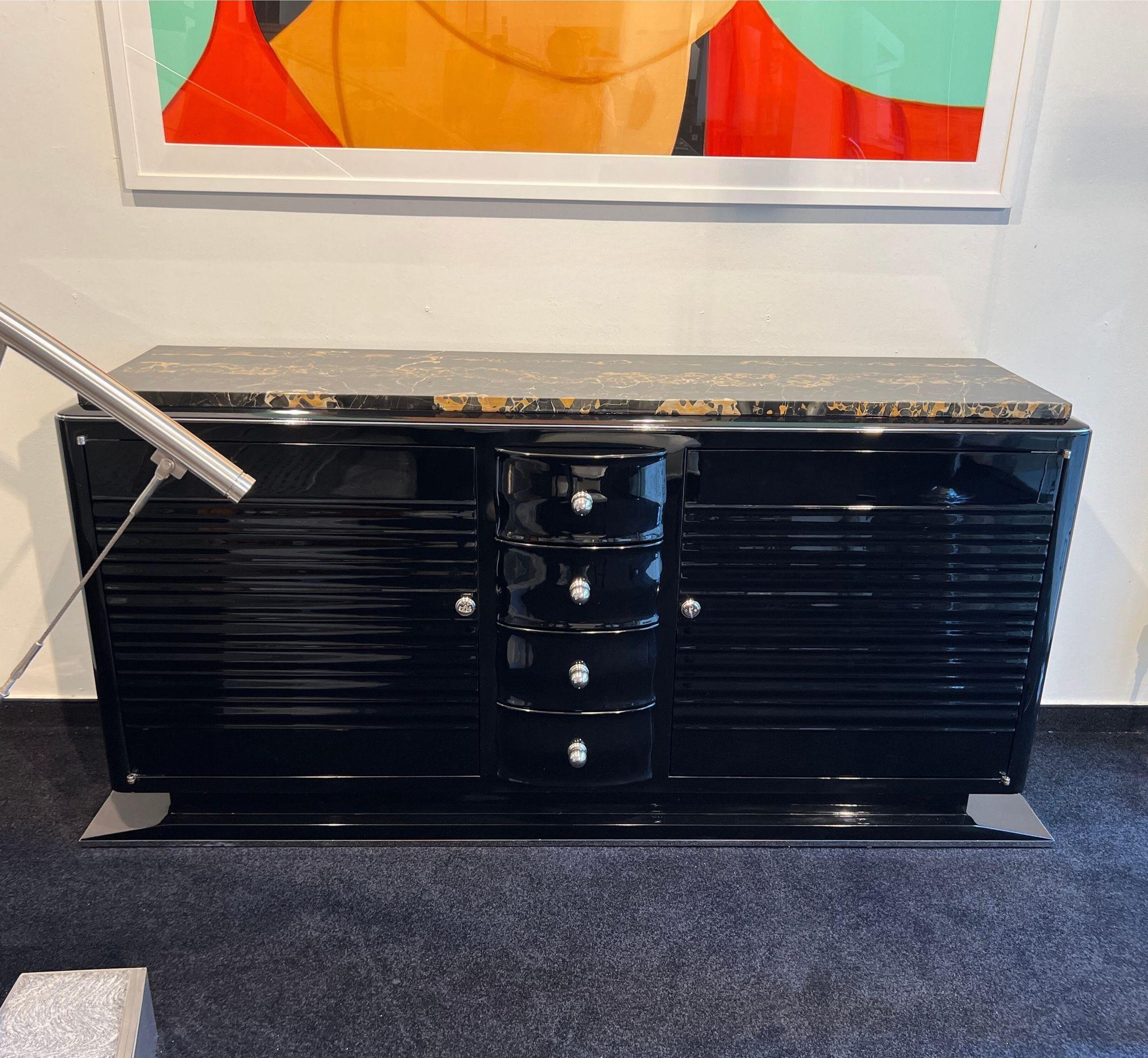 Large, modernist Art Deco Sideboard by Gaston Poisson from France, circa 1935.

High-gloss black piano lacquer on solid mahogany wood.
Two front doors with flutings. Four drawers in the middle with chrome-plated knobs.
Interior and shelves in