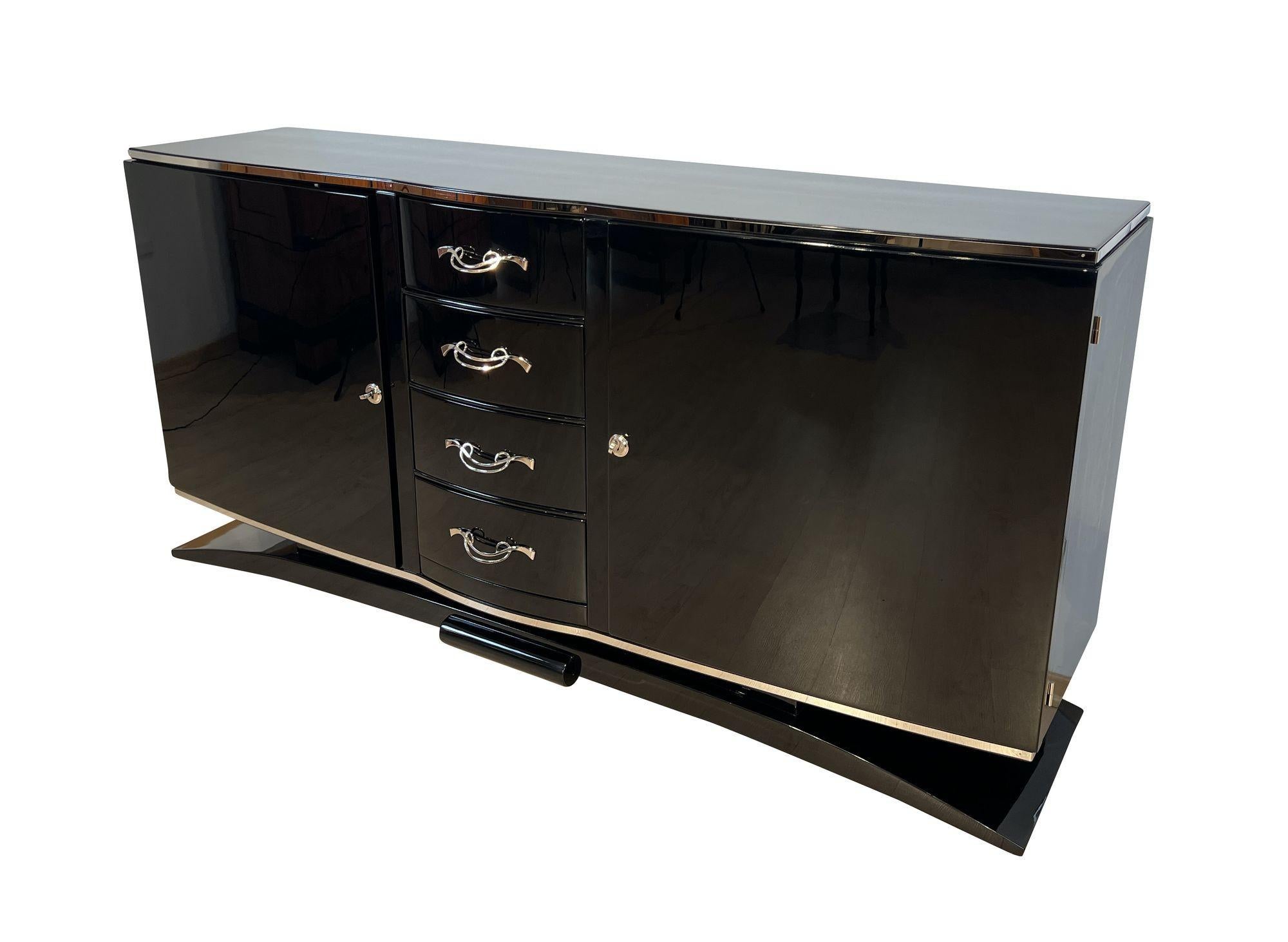 Large original Art Deco Sideboard of Buffet in black piano lacquer from France around 1930.
Black high gloss piano lacquer on walnut wood. Polished stainless steel trims running around the top and bottom of the body
Elegantly curved base that lifts