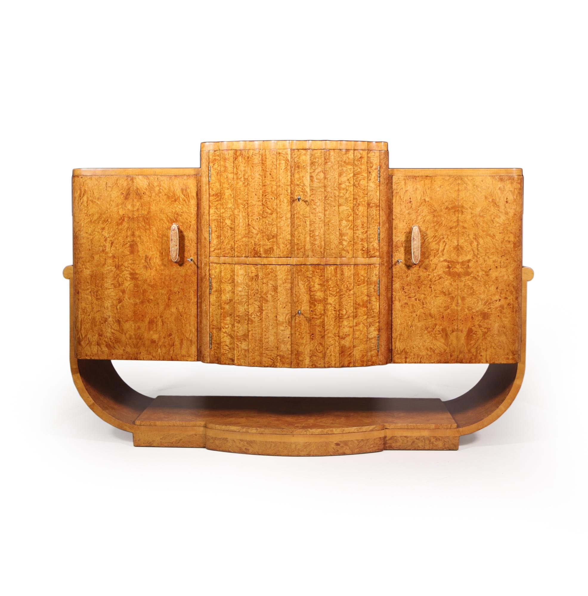 A stunning Burr Maple cocktail cabinet sideboard by Harry and Lou Epstein produced in London in the 1930’s, the sideboard has a center fluted door cocktail section with lift up lid this is all lockable this is flanked by two outer storage cupboards