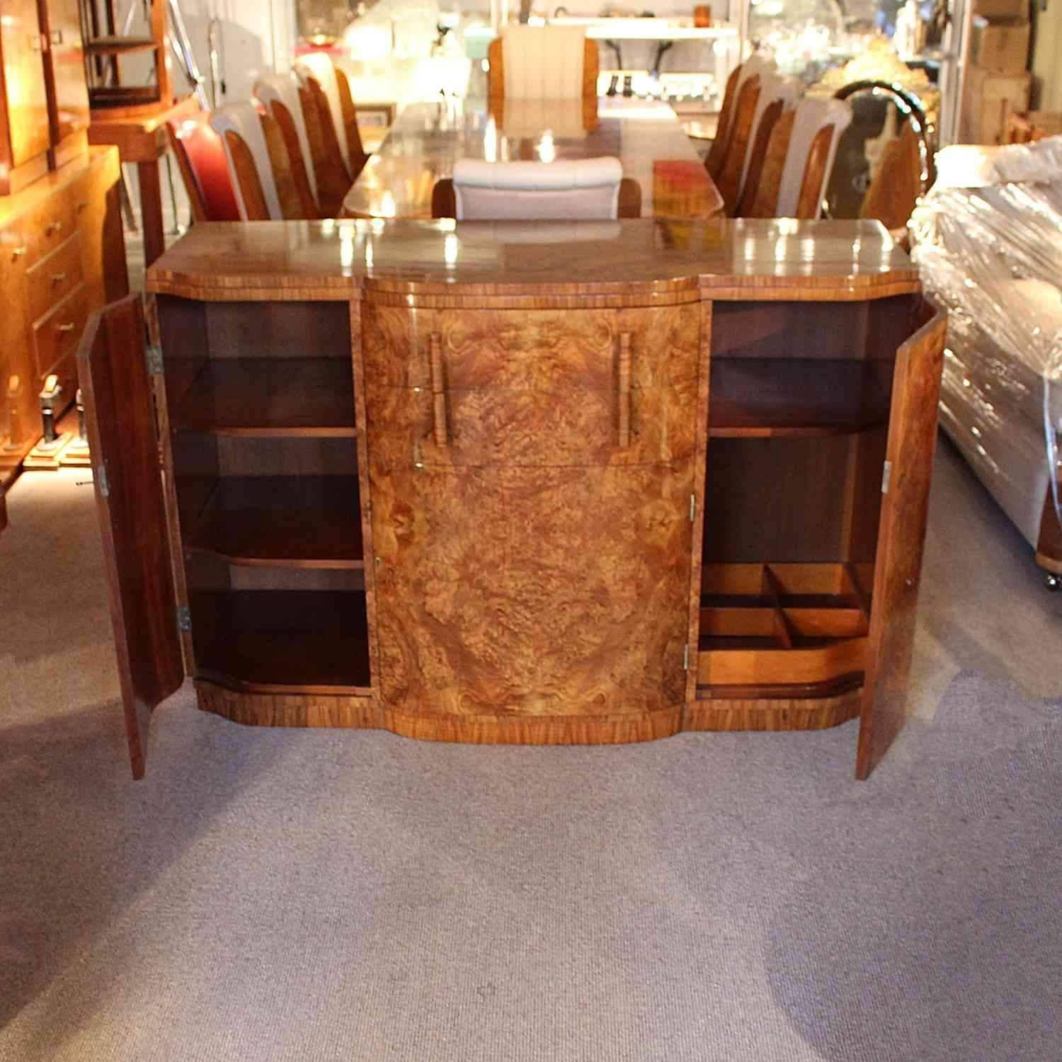 An Art Deco sideboard with central drawer and cabinet, shelved cabinet to left and cabinet with bottle holder to right. Figured burr walnut throughout with straight grain walnut handles.

 