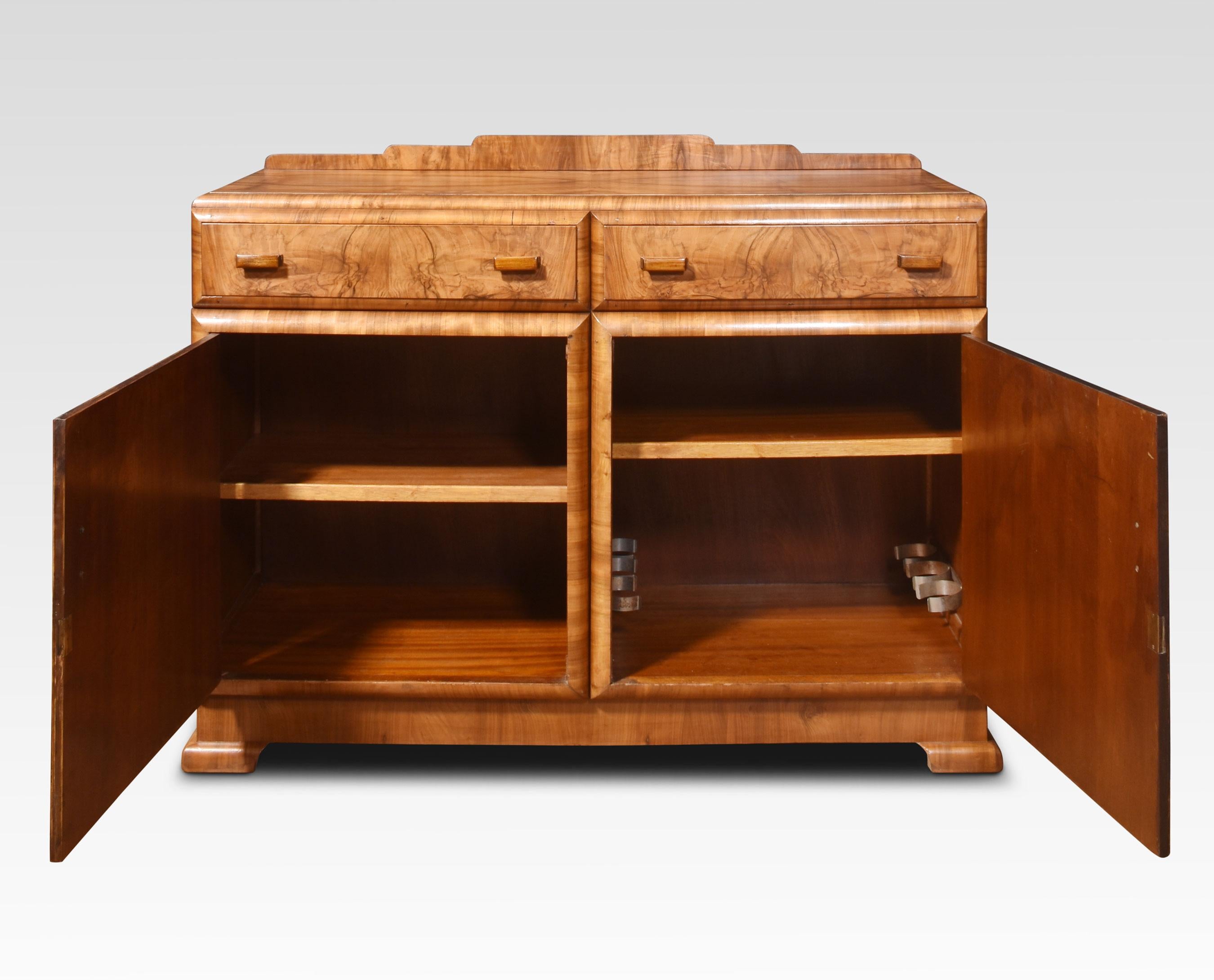 Art deco sideboard the raised gallery back to the large rectangular well figured walnut top. Above two long freeze drawers with stylised handles.Above two cupboard doors opening to reveal plenty of storage. All raised up on bracket