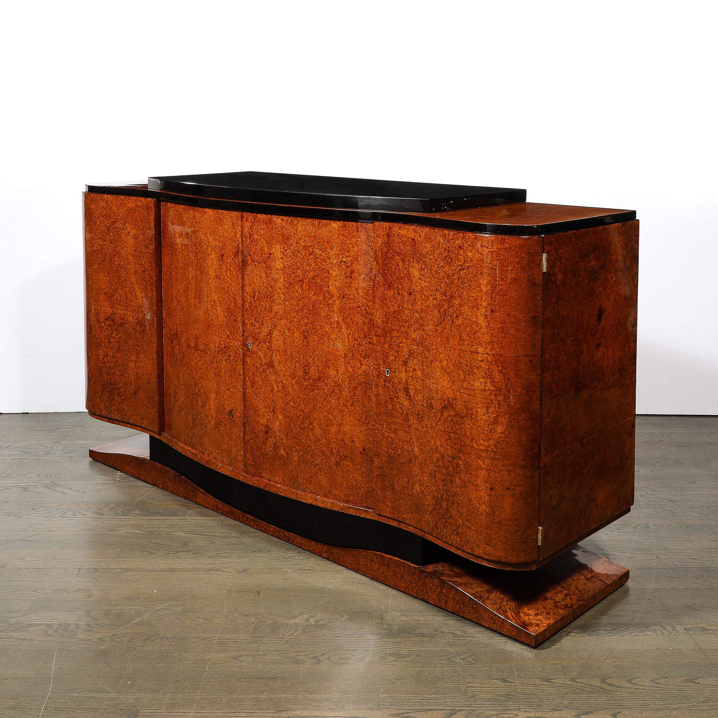 This elegant and exquisitely made Art Deco Sideboard in Burled and Bookmatched Amboyna Wood W/Black Lacquer Detailing and Plinth Base originates from France, Circa 1935. Features a wonderful compostion of elegant curves and well proportioned