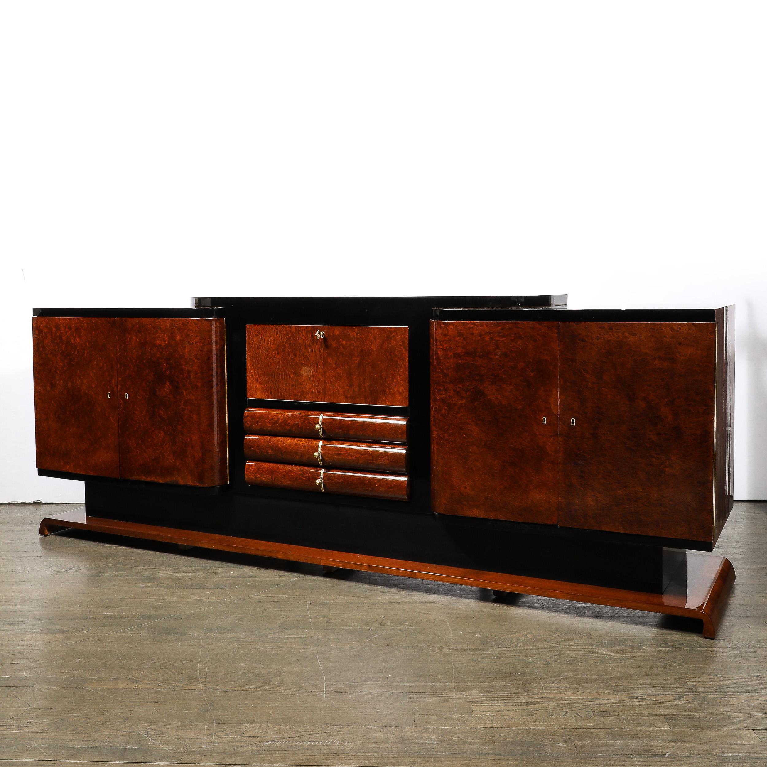 This remarkably beautiful Art Deco Sideboard in Bookmatched & Burled Amboyna Wood, Mahogany, & Walnut Base with Black Lacquer Detailing & Brass Fittings originates from France, Circa 1925. A monumental and stunningly made case piece, this sideboard