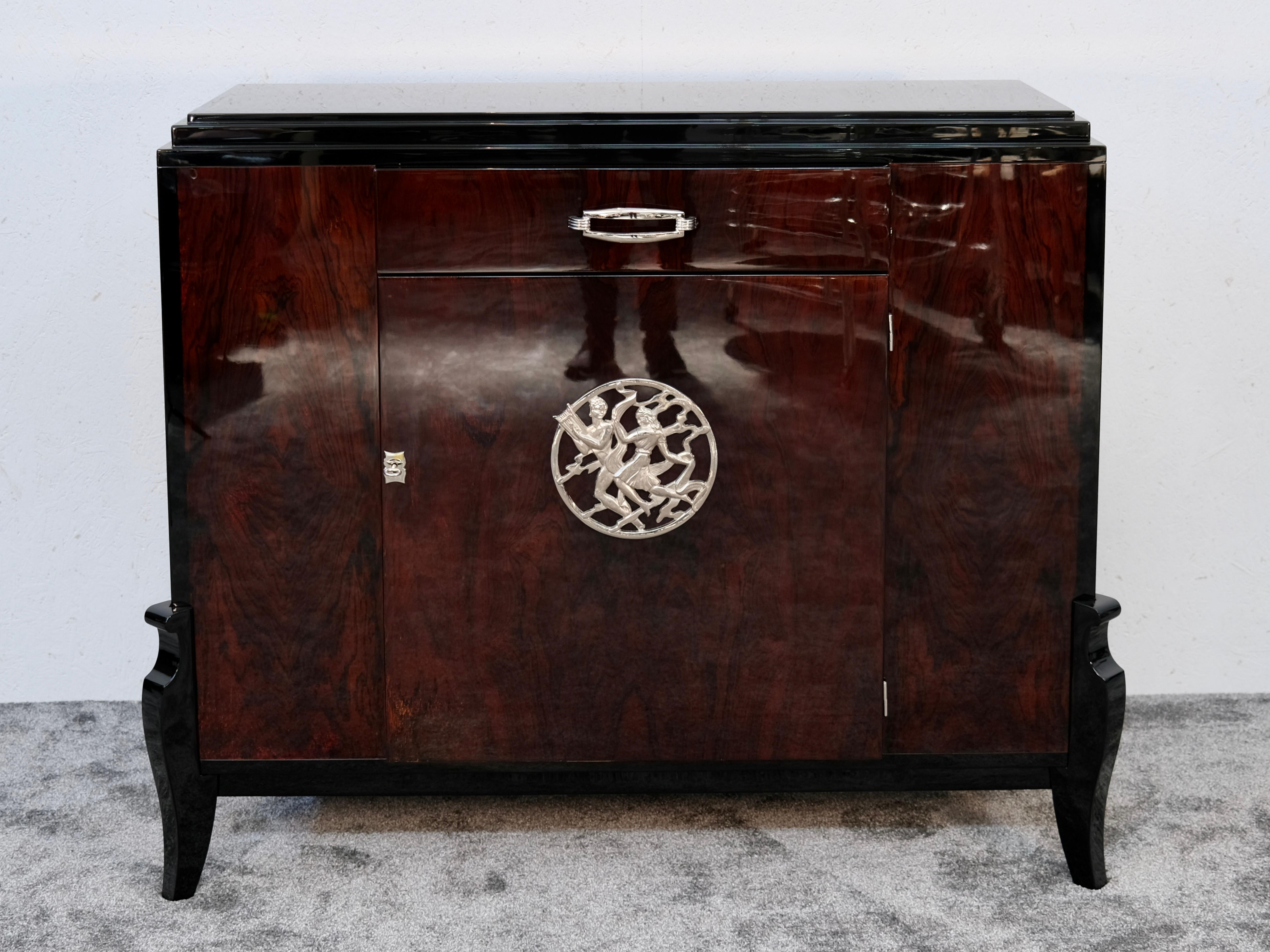 Ein Stück voller Präsenz und Souveränität: Diese originale französische Anrichte im Art déco-Stil, die um 1930 entstanden ist, schafft ein Gleichgewicht zwischen architektonischer Klarheit und ornamentaler Finesse. Die hochglänzende Oberfläche des