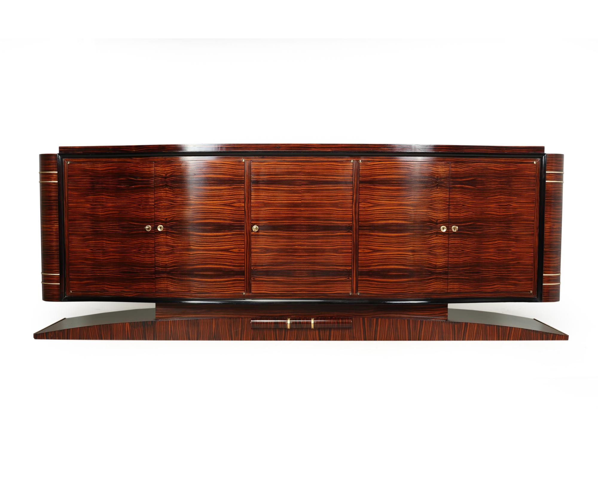 A very large Art Deco serpentine fronted sideboard produced in France in the 1930, it has fine grain Macassar ebony to the exterior and lined with blonde Chestnut to the interior, it has five doors the center has a drawer behind and a bottle shelf
