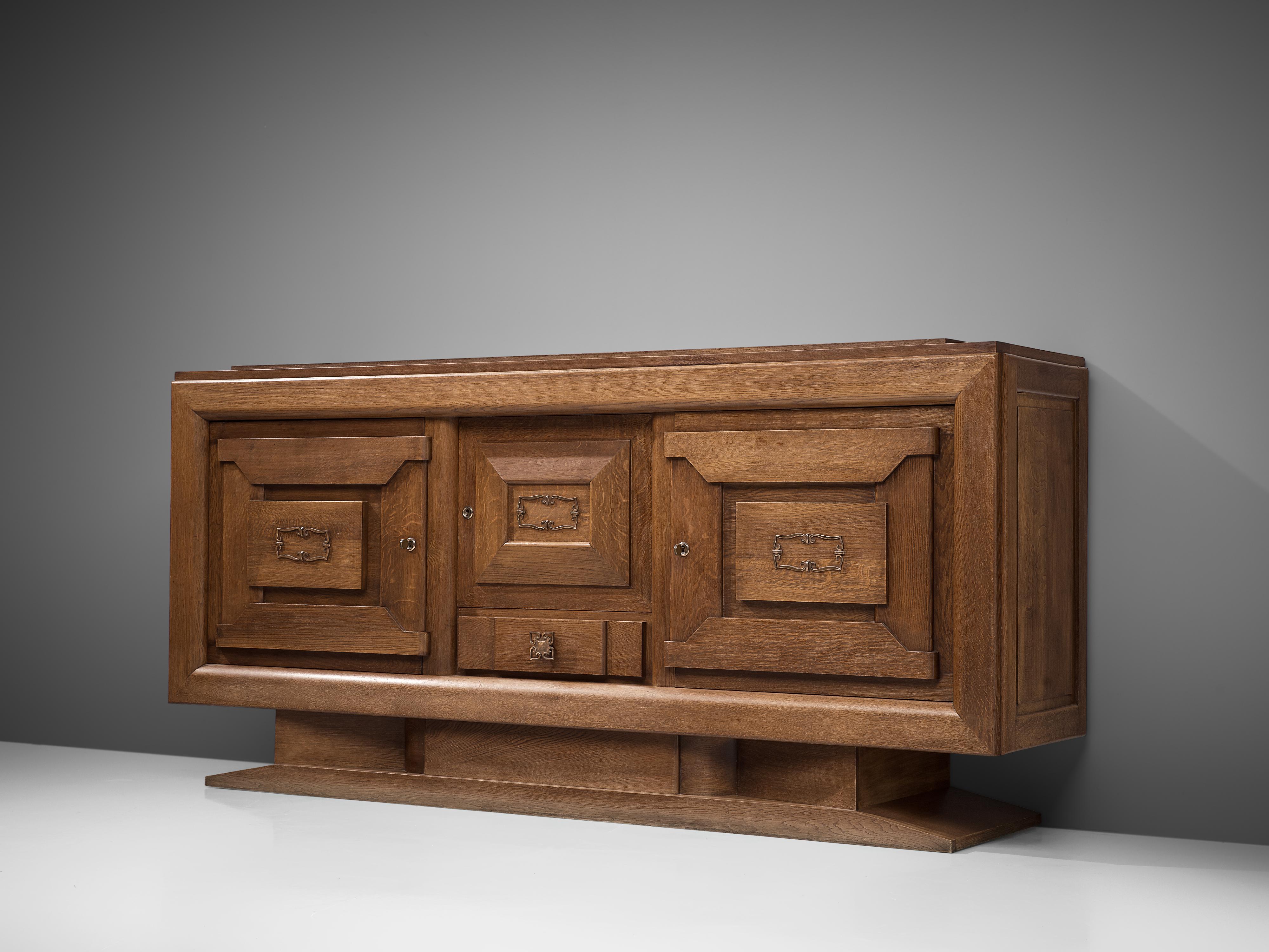 Charles Dudouyt, sideboard, oak, France, 1930s

French Art Deco credenza designed by the decorator Charles Dudouyt. The solid wooden frame gives this sideboard a sturdy character. The door panels show a geometric pattern of solid natural wooden