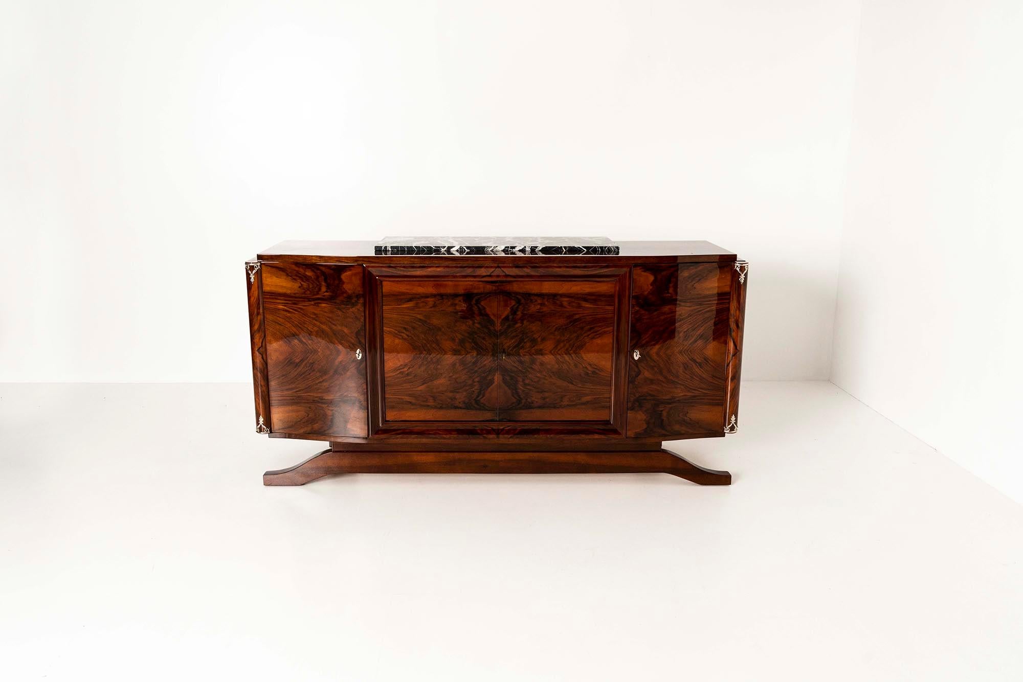 A very eye-catching French Art Deco sideboard of size and precisely manufactured in the 1930s. The highest quality walnut wood has been used for this copy. On all four door panels, the veneer, which shows a dramatic drawing, is beautifully mirrored.