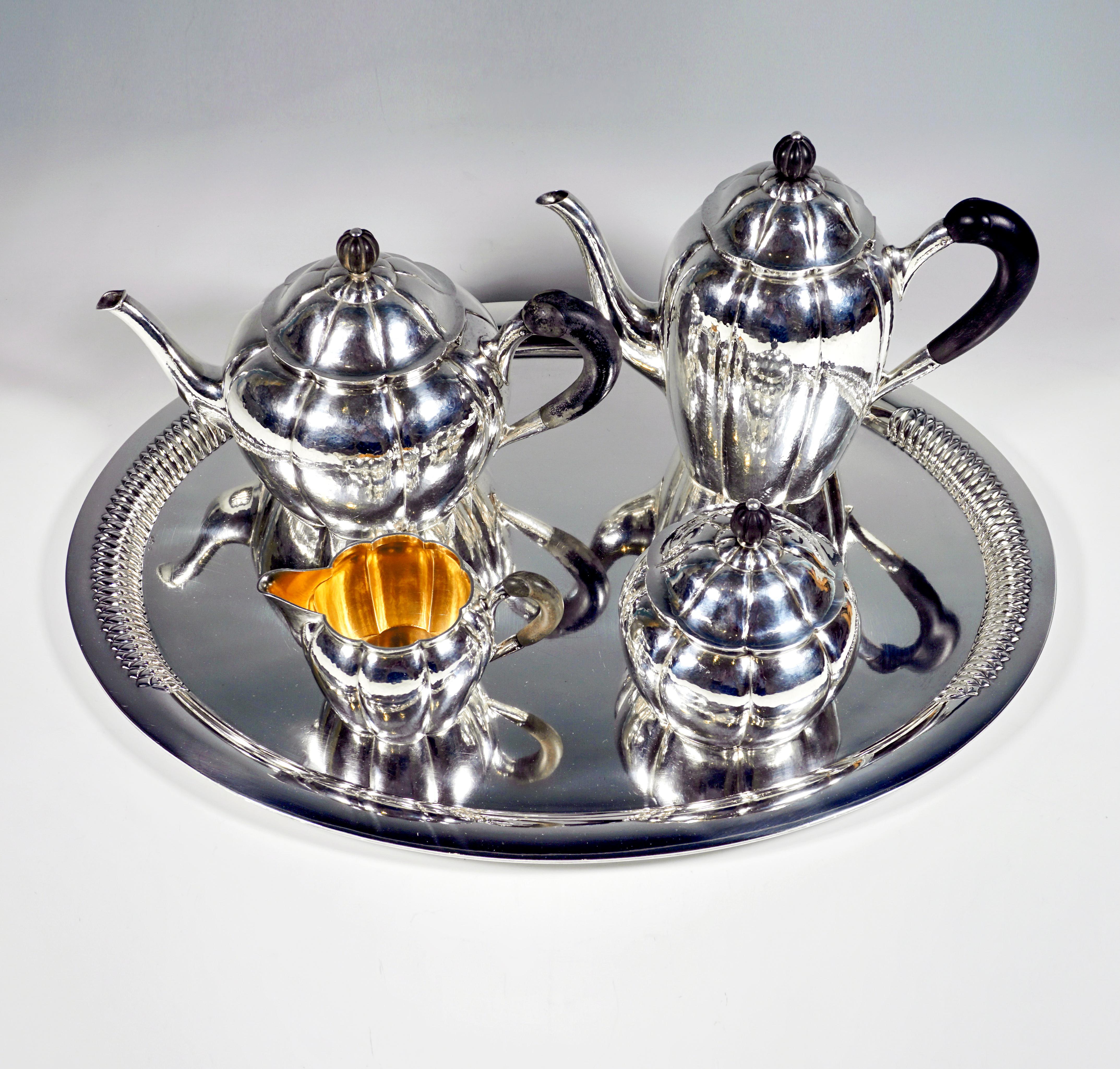 Elegant 5-piece silver centerpiece consisting of a coffee pot, teapot, milk jug, sugar bowl and a tray.
Bulbous, raised vessels, narrowing again towards the opening, with a vertically raised rim on a flush stand, surface subtly hammered, walls