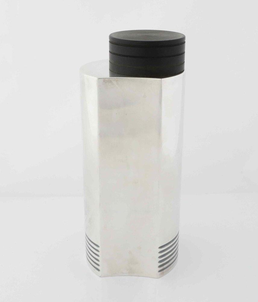 This modernist looking Art Deco cocktail shaker is silver plated with a bakelite cap. Clean lines, asymmetrical composition and elegant engraved lines at the base are the selling point of this item. It is an iconic piece that will make a tasteful