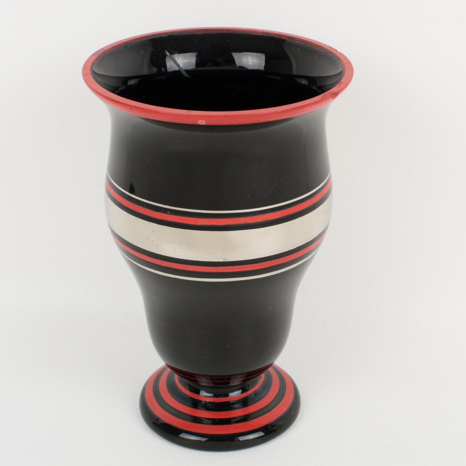 Questo elegante vaso in vetro opalino nero French Opaline degli anni '30 presenta una decorazione a deposito in argento e rosso con un motivo geometrico. Non c'è alcun marchio visibile del designer.
Il vaso è in ottime condizioni originali con