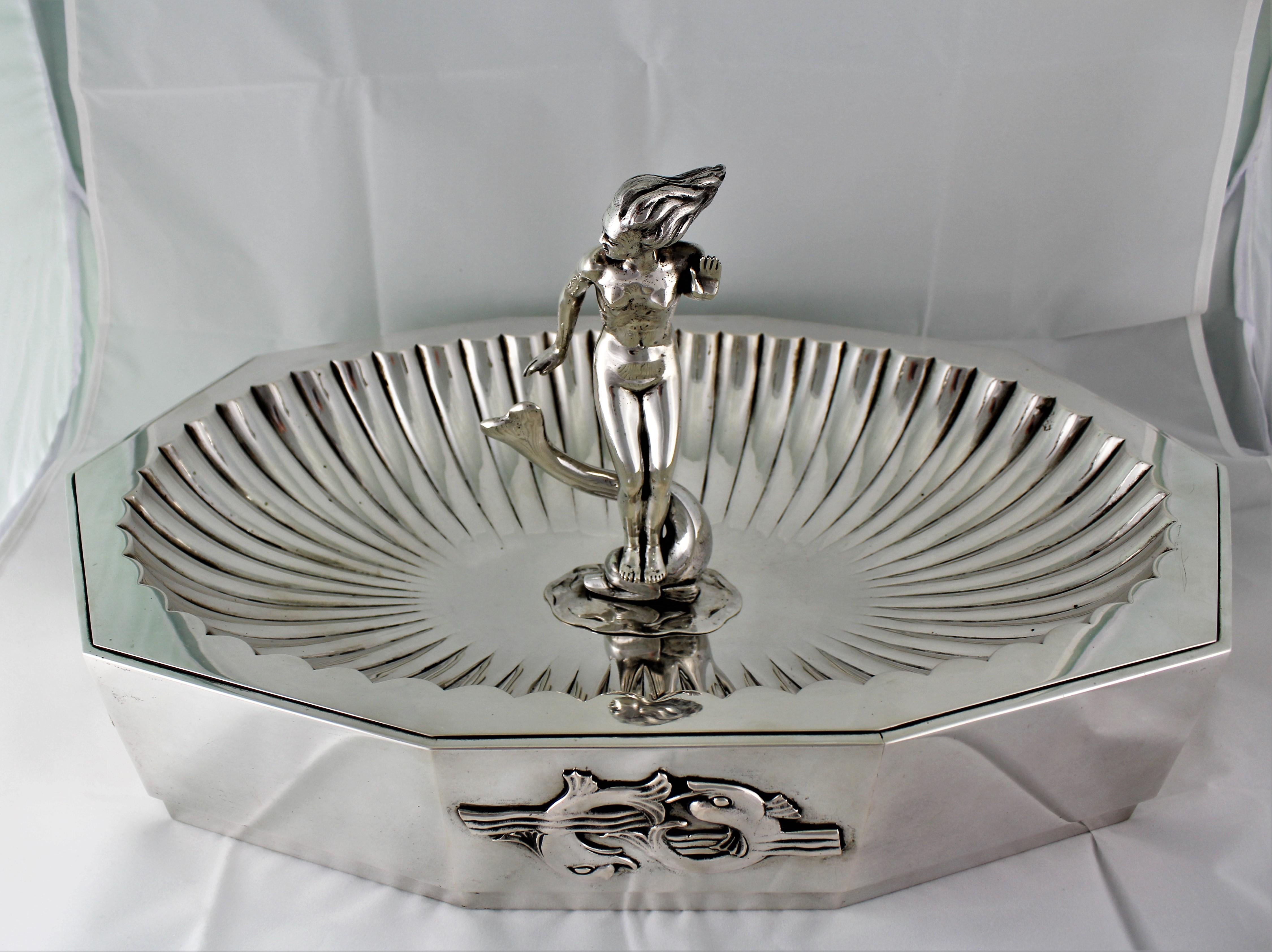 Arrigo Finzi Art Deco centerpiece - Design By Futurist Architect Sant'Elia Antonio
Milan 1938 - 1943
Wonderful silver centerpiece Fountain like and octagon shaped embossed by hand.
In the middle a sculpture of a woman standing on dolphin (she