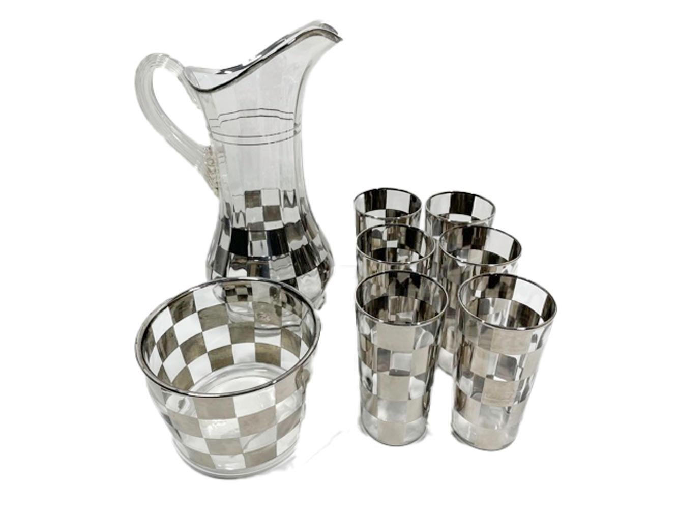 Nine-piece Art Deco cocktail suite consisting of a chrome lidded cocktail shaker, handled cocktail/water pitcher, ice bowl and 6 highball glasses. All decorated with silver in a checker pattern on optically ribbed clear glass.