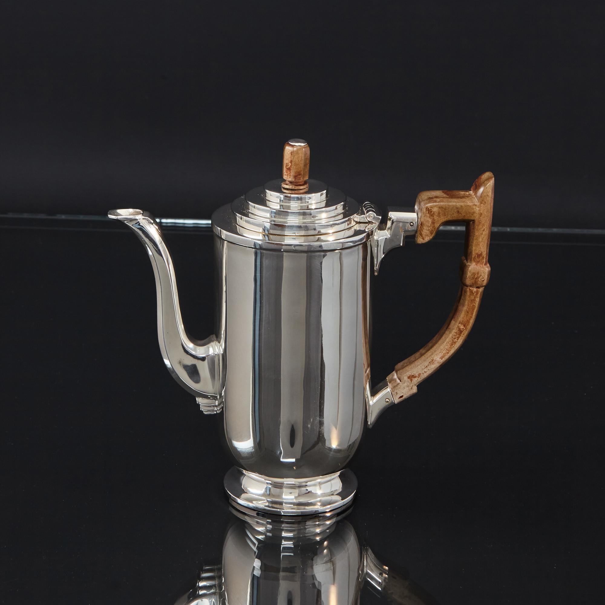 Very stylish silver coffee pot with wooden handle and finial, featuring all the design motifs of the Art Deco era . The stepped lid, elongated finial, panelled spout and handle all personify the design cues of the era. The round body is of straight
