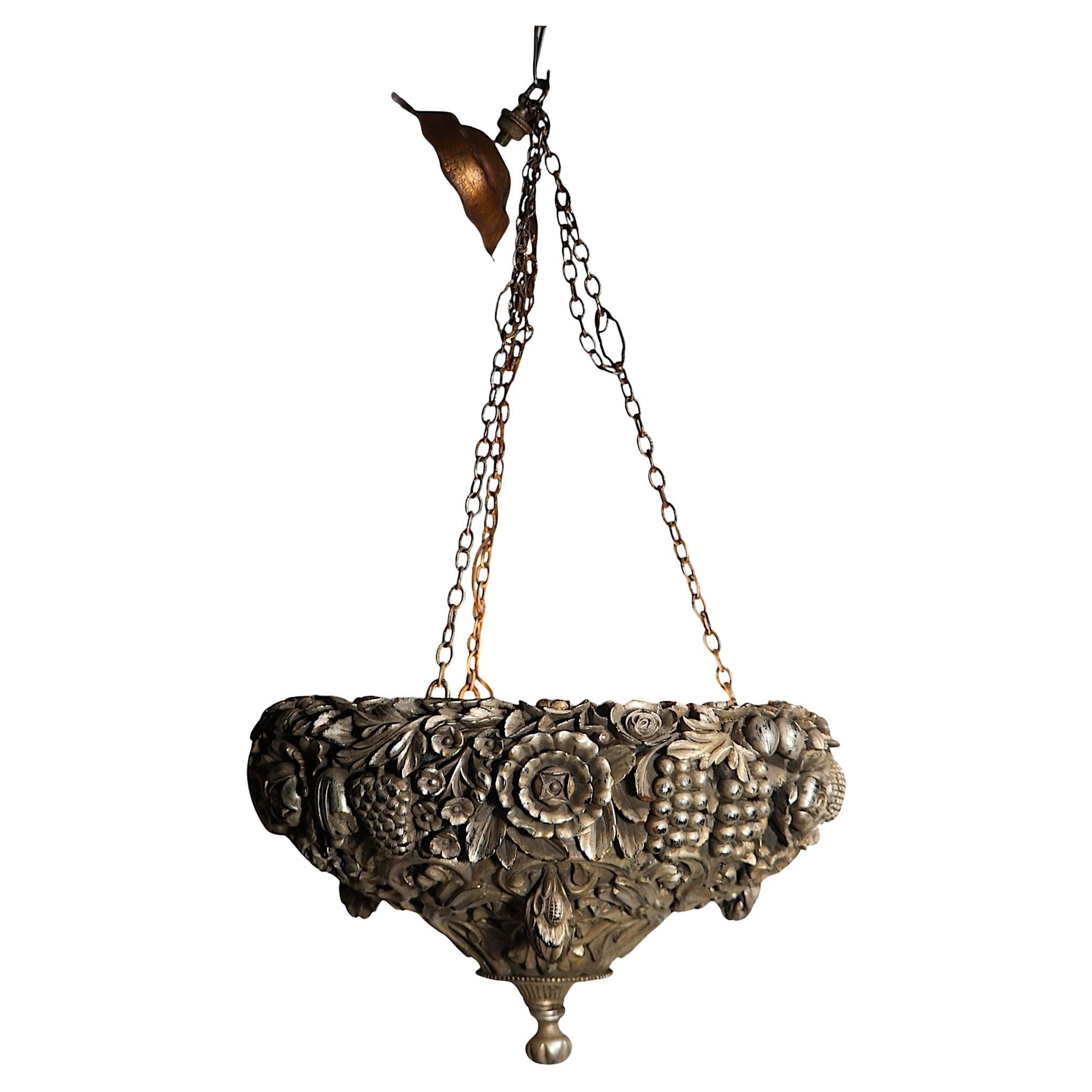 Voguish, chic, and sophisticated carved wood inverted bowl hanging fixture, by James Mont. The chandelier features an intricate and finely detailed allover foliate motif in original silver gilt finish, suspended by three chains, which gather at the