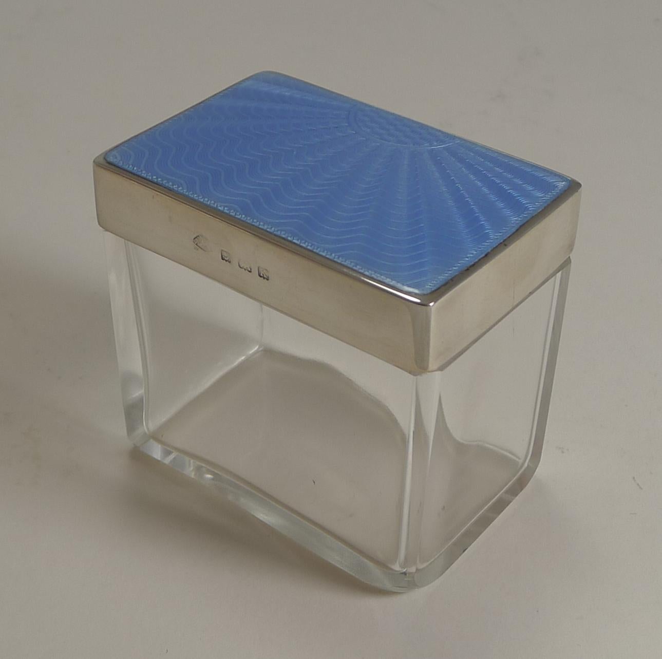 A fabulous vintage Art Deco vanity box made from a clean crystal and topped with a sterling silver lid hallmarked for Birmingham 1934; the makers mark is also present for the silversmith's, Adie Brothers.

The top of lid is decorated with a