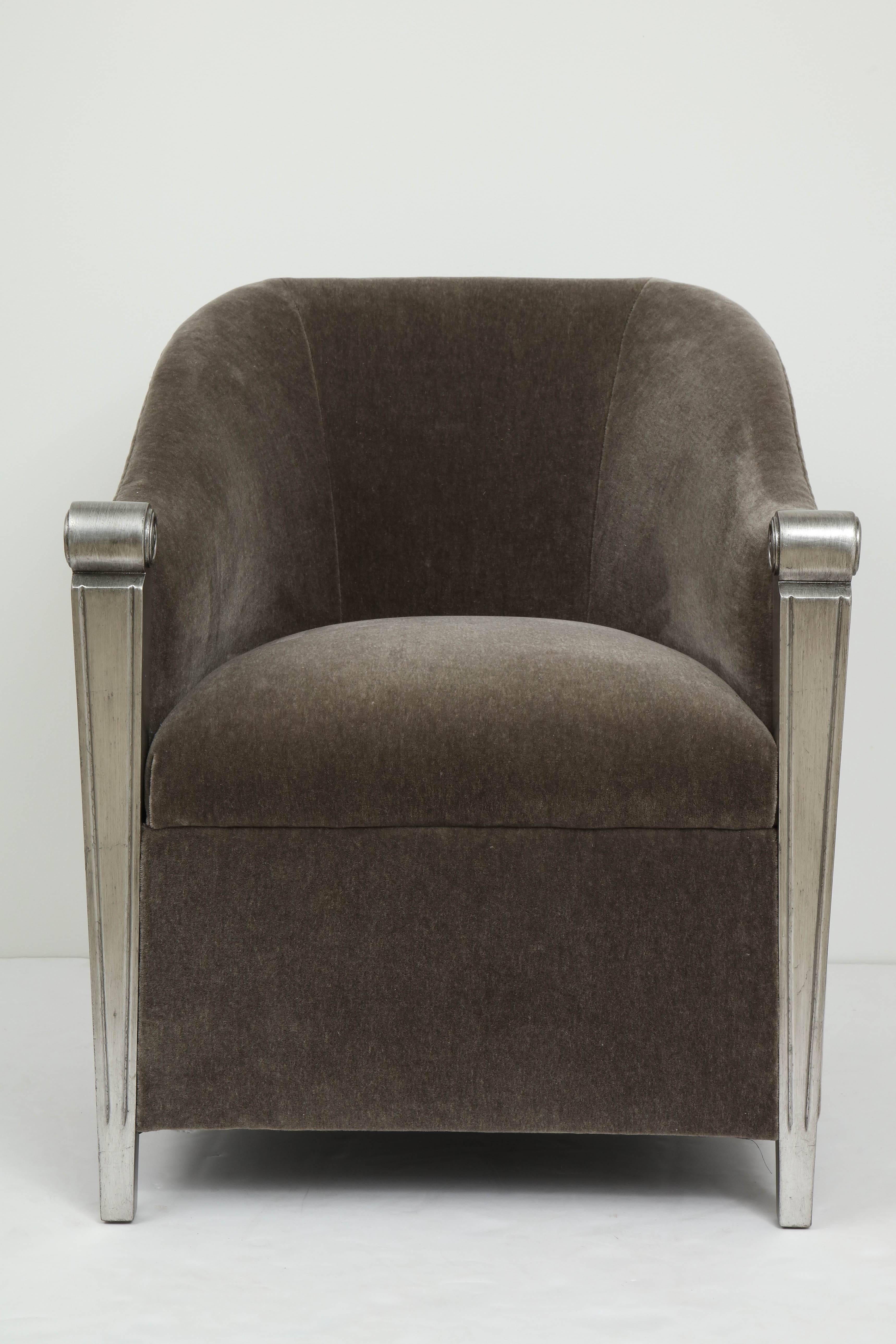 Stunning pair of aged silver leaf framed club chairs with new plush, medium grey mohair upholstery. Chairs have a barrel back silhouette and two splayed back legs. Chairs are in mint restored condition.