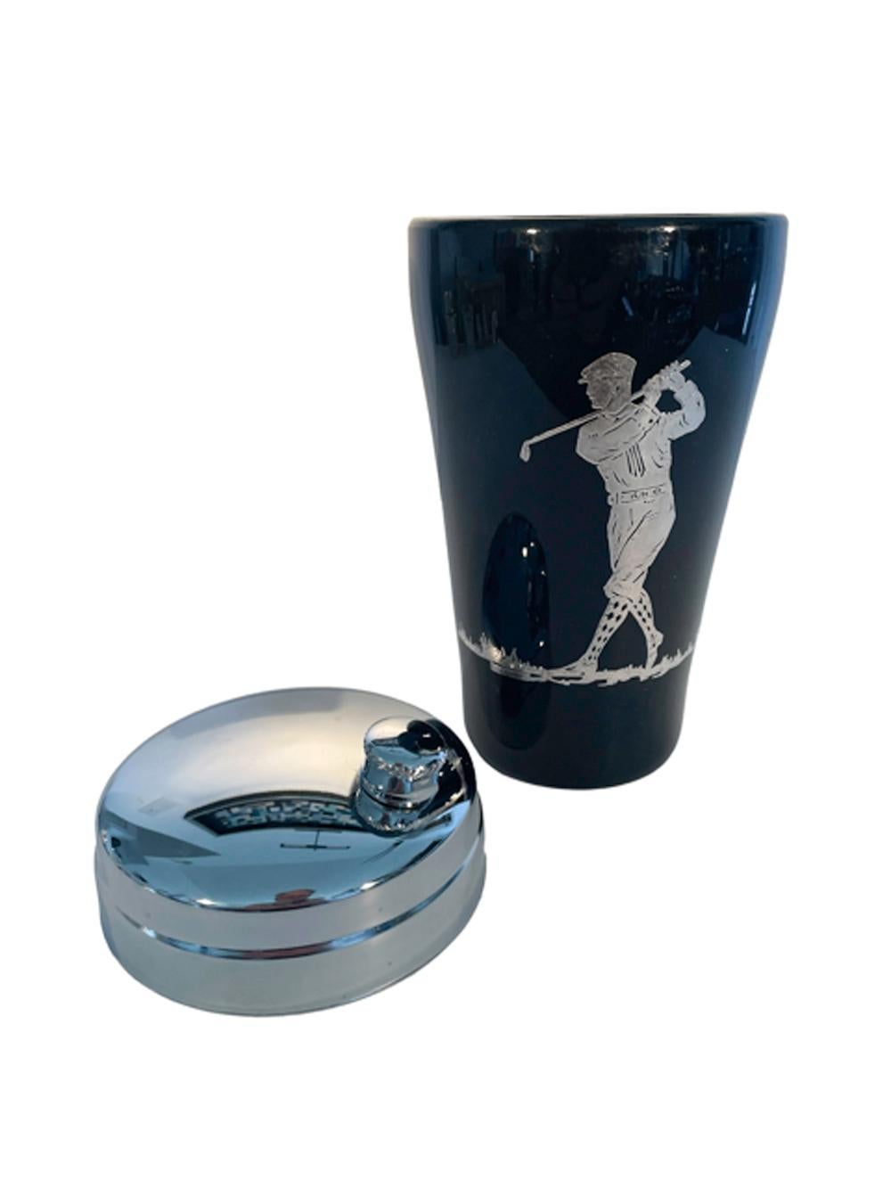 Art Deco golf theme cocktail shaker in opaque black class with a polished foot, decorated with a golfer in silver overlay and having a chrome lid.