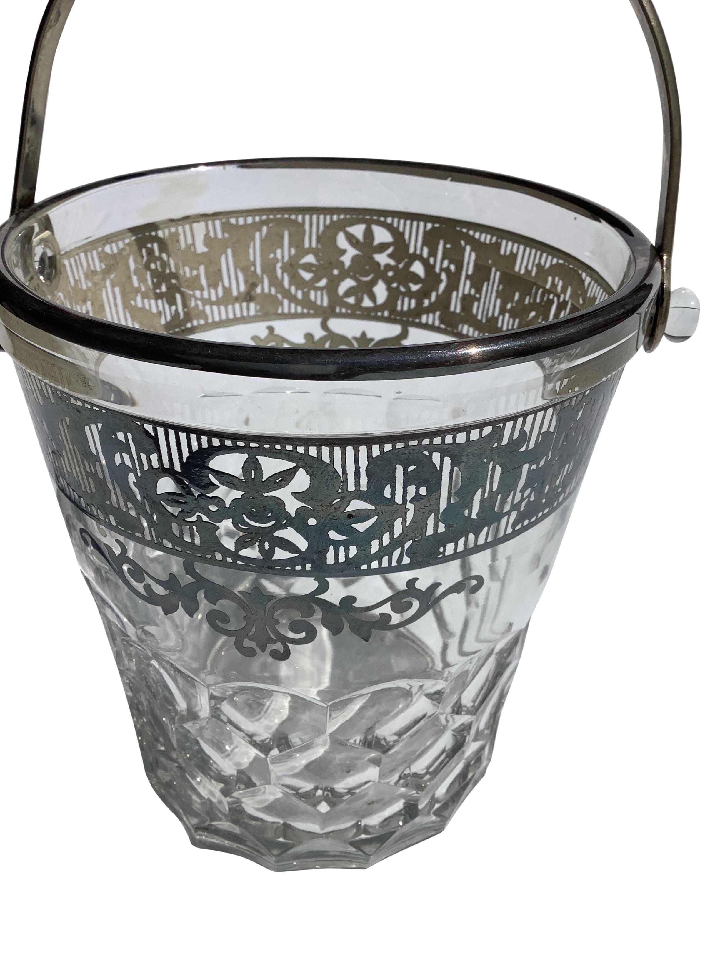 Art Deco glass ice bucket with a nickel handle. Molded bucket with a faceted design. Top of bucket has silver overlay band with intricate pierced design.
