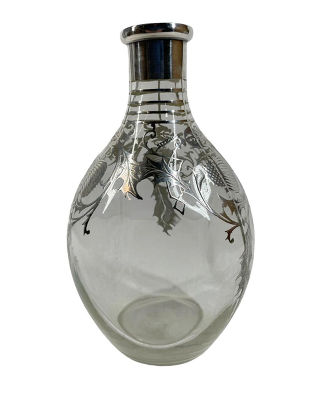 Art Deco clear glass pinch decanter, dimpled on three sides and with silver overlay grid around the neck and a silver overlay collar, the shoulders and sides decorated with thistle leaves and flowers with the word sterling incorporated into the