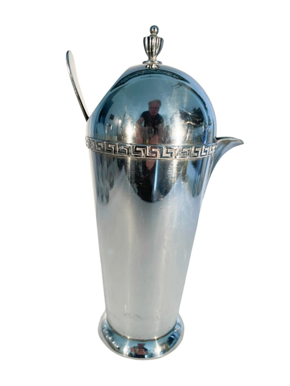 Art Deco silver plate cocktail pitcher of tapered form on a ring foot and having a domed top with urn finial above a Greek key band, the fixed dome top with an opening at back for filling and stirring, a pour spout with integral strainer is opposite