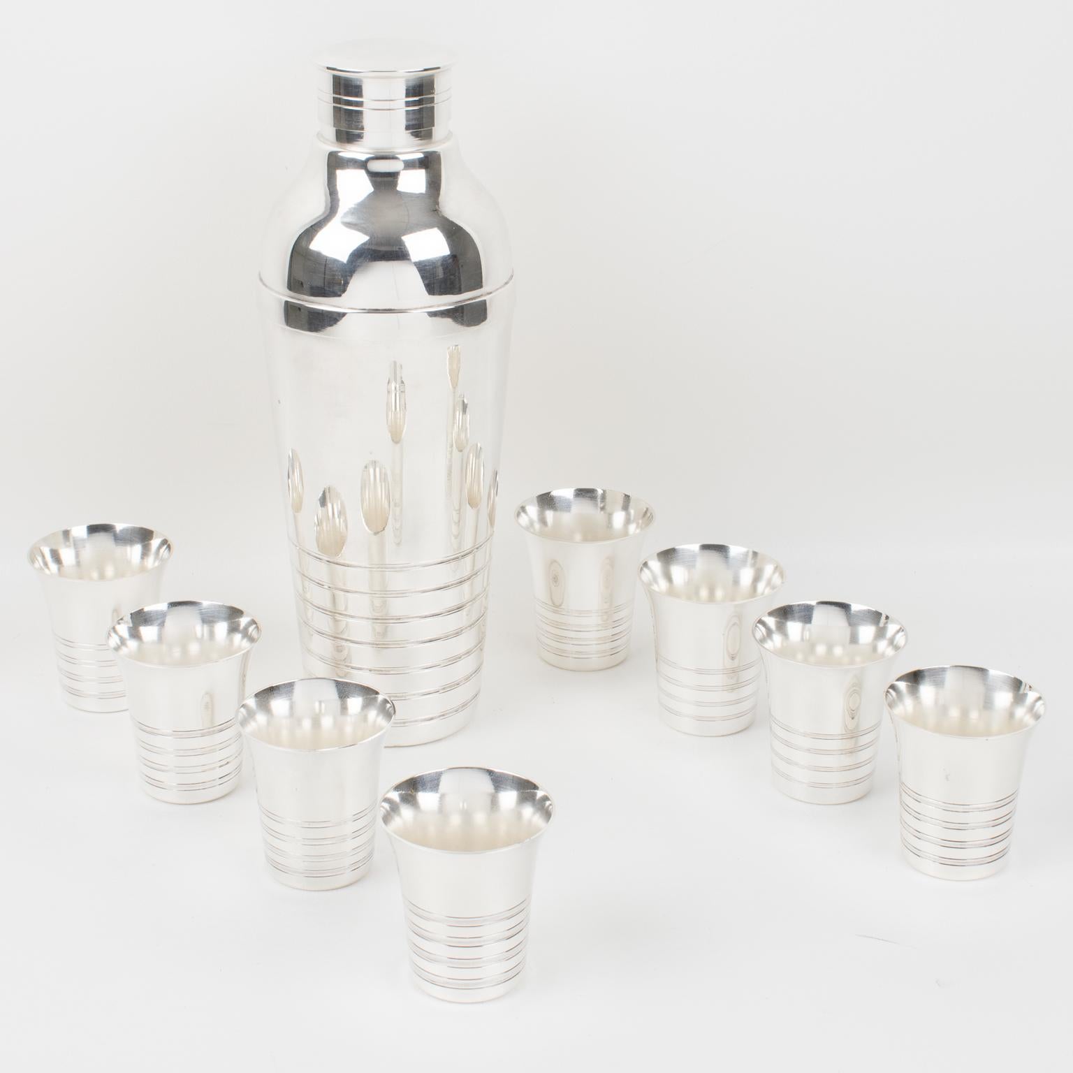 This elegant French Art Deco silver plate barware serving set was designed by Silversmith Maison Montagnon, Lyon. The three-sectioned designed cylindrical cocktail or Martini shaker has a removable cap and strainer. The bar set is completed with